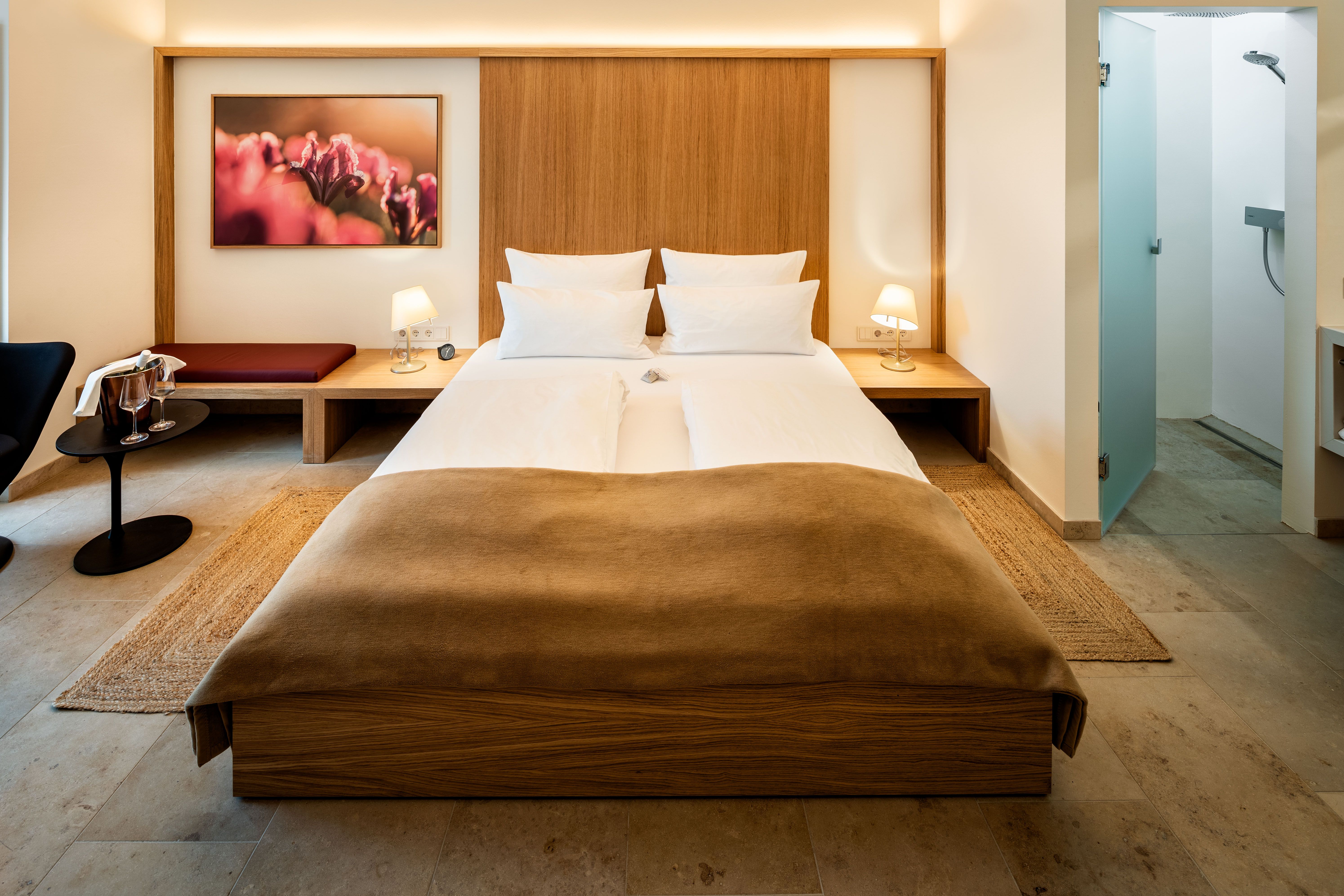 Ein modernes Zimmer mit Doppelbett, Holzelementen, Sitzbank und einer Glastür.