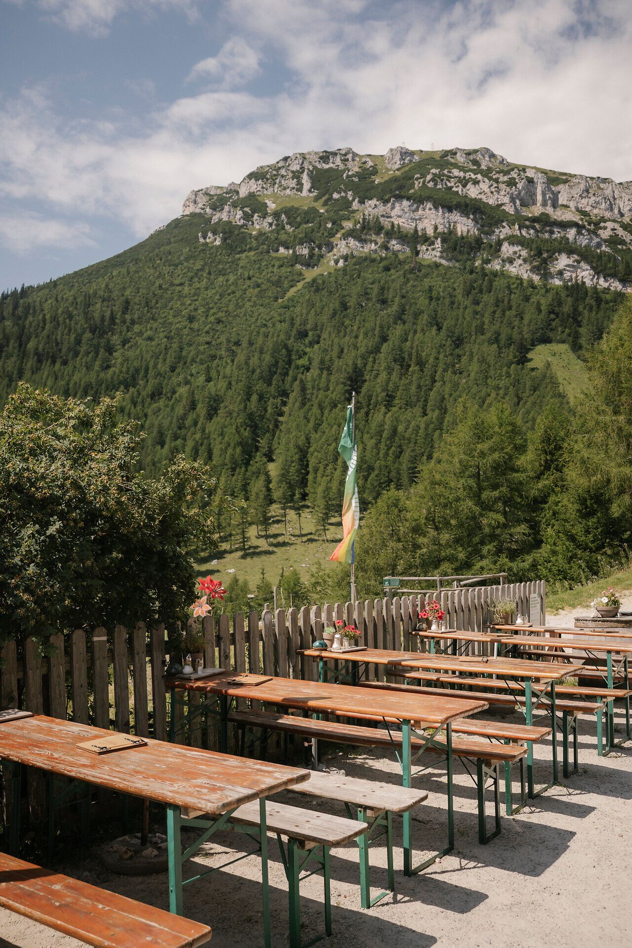 Sonnige Terrasse des Waxriegelhauses auf der Rax mit Holztischen und Blick auf die umliegende Berglandschaft