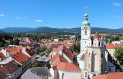 Ausblick auf Neunkirchen mit Häusern, Kirche und Bergen im HIntergrund.