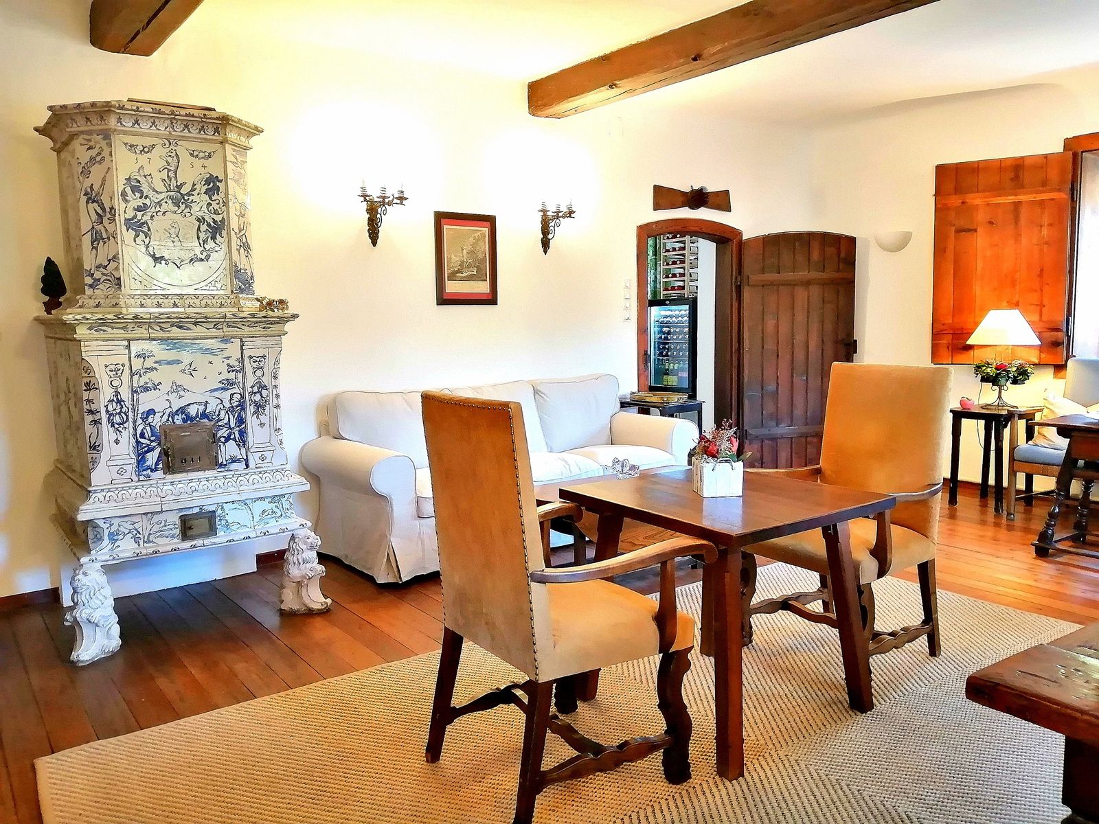 Gemütlicher Raum mit antikem Kachelofen, Holzmöbeln und Teppich.