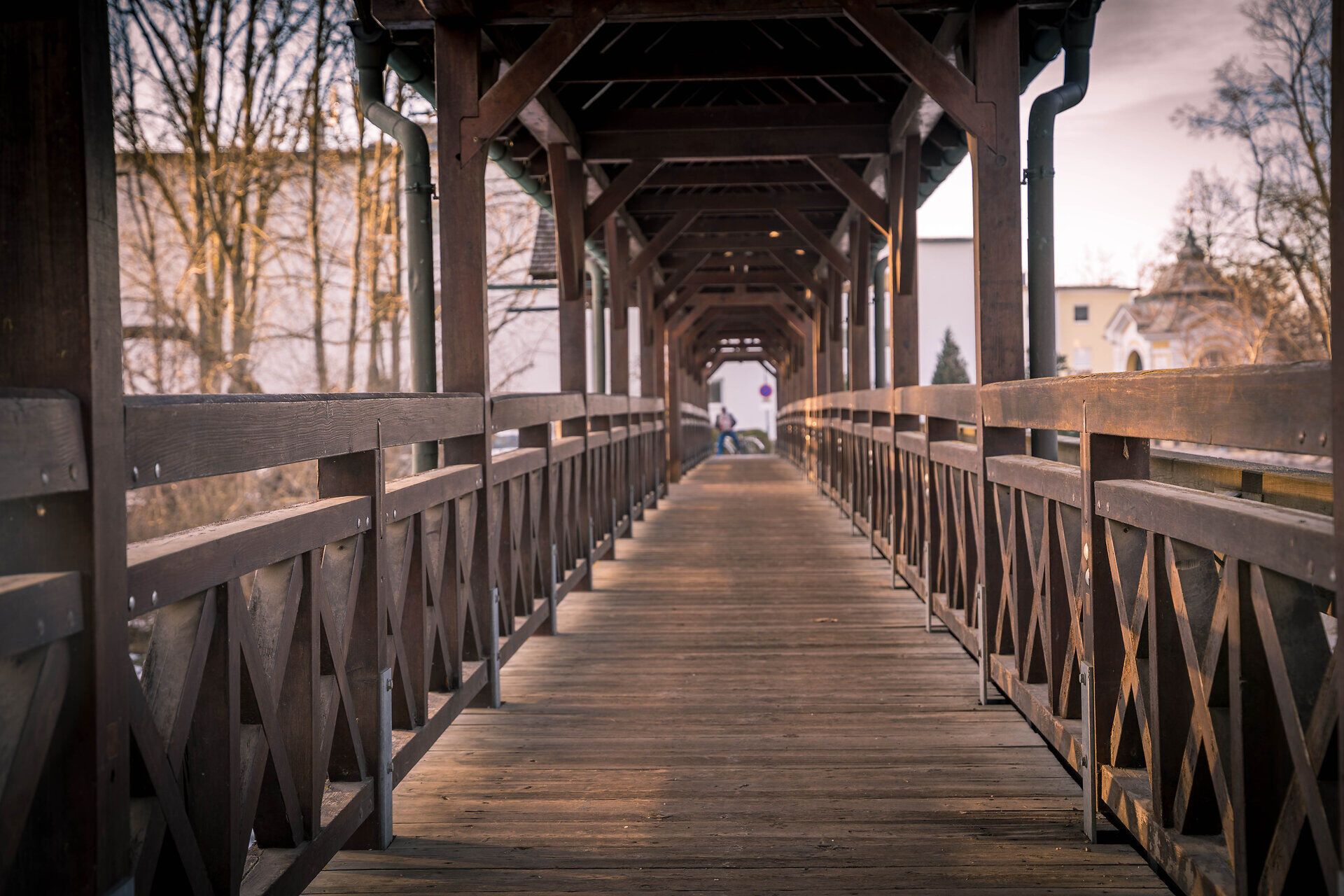 Eine überdachte Fußgängerbrücke aus Holz führt über die Leitha.