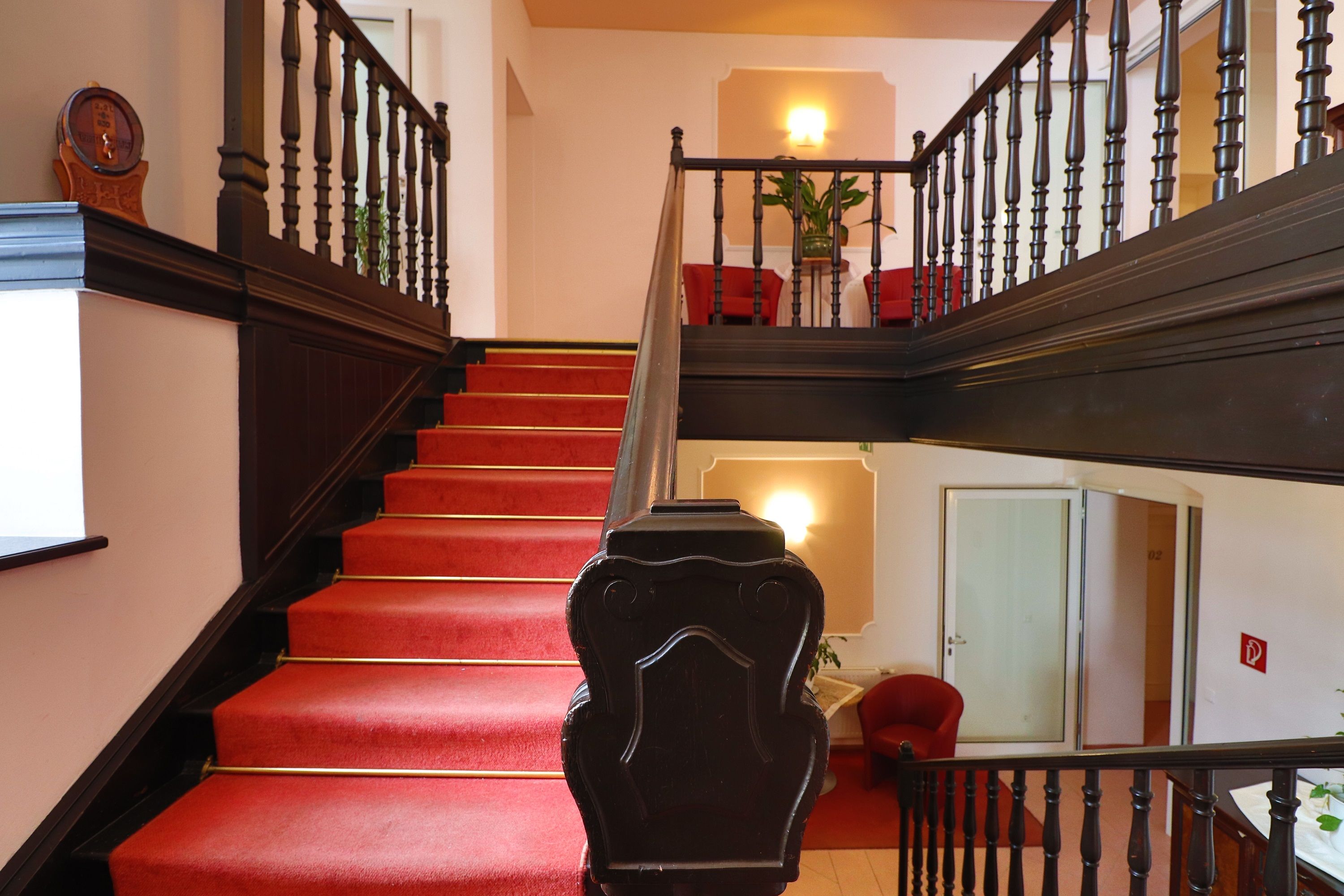 Hotelstiegenaufgang mit rotem Teppich und dunklem Holzgeländer.