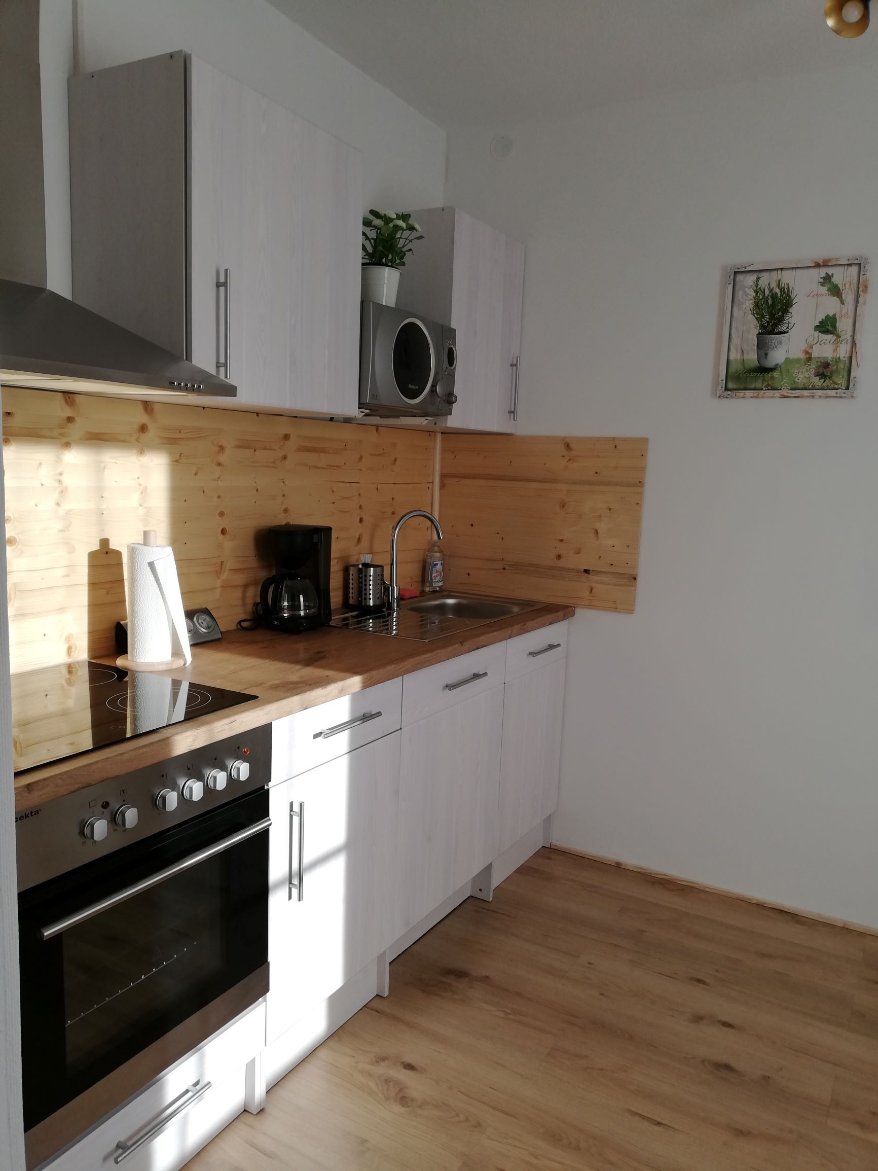 Moderne Küche mit Holzverkleidung, weißen Schränken und Geräten.