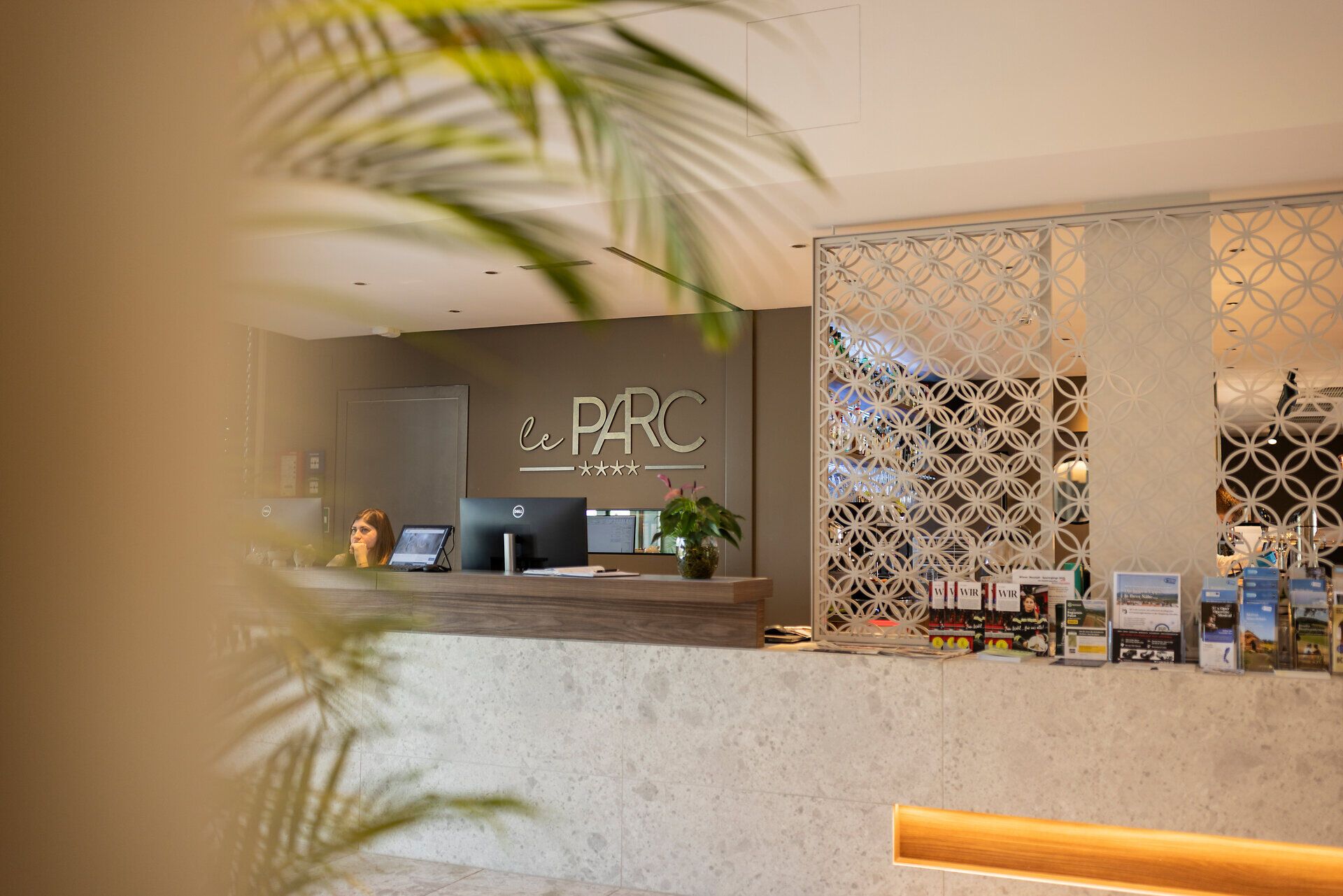 Modern eingerichtete Rezeption des Hotel leParc mit dekorativer Trennwand und diversen Prospektenaufstellern.