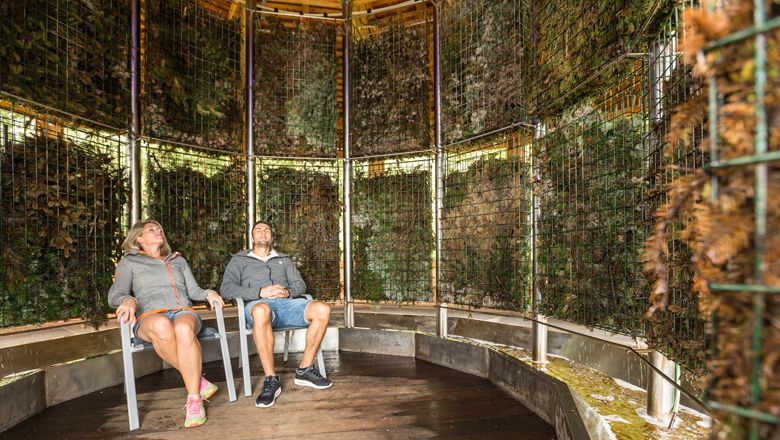 Zwei Personen sitzen entspannt in einem Gradierwerk.