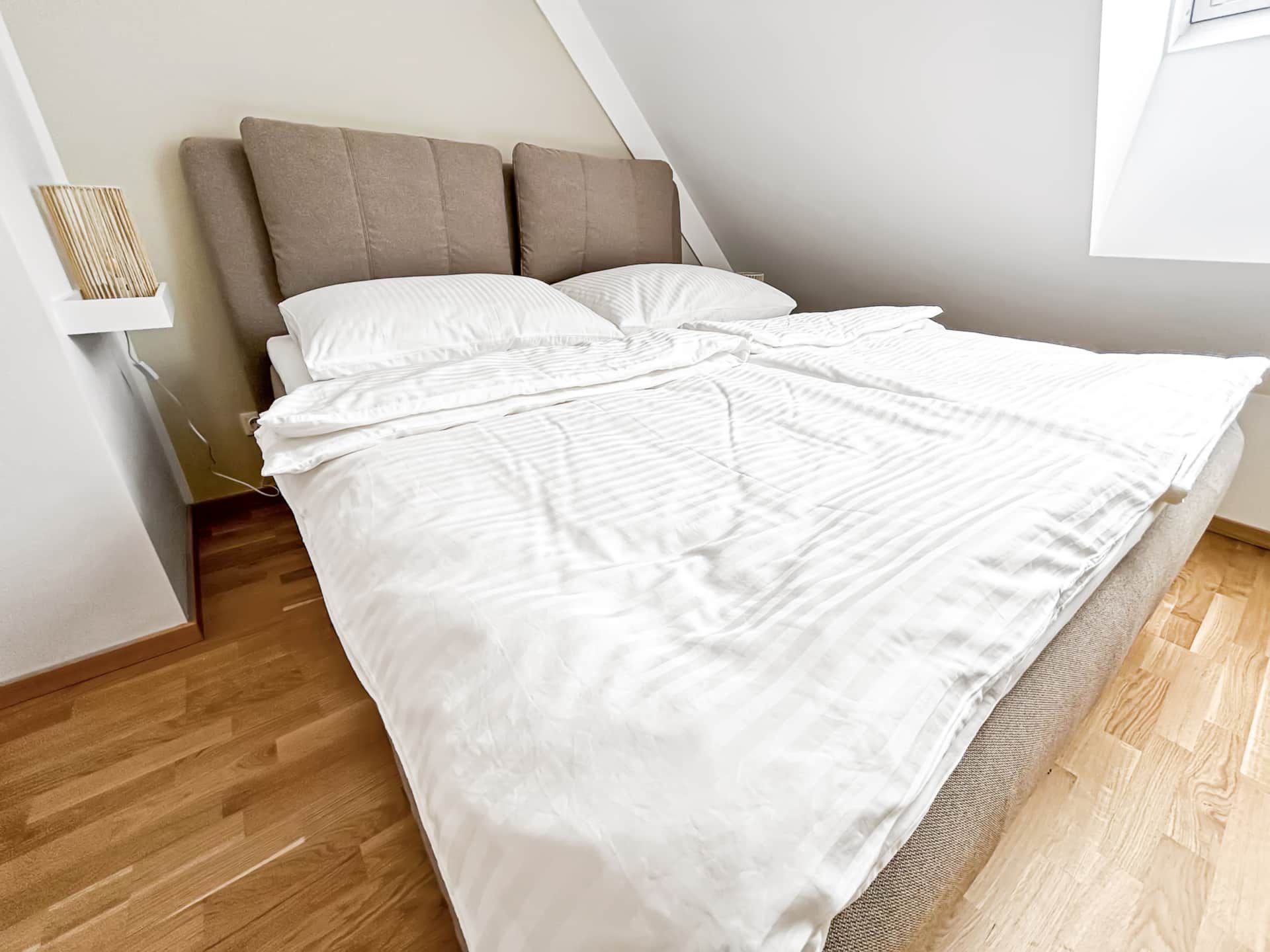 Bedroom with double bed under a slightly sloping roof with window.