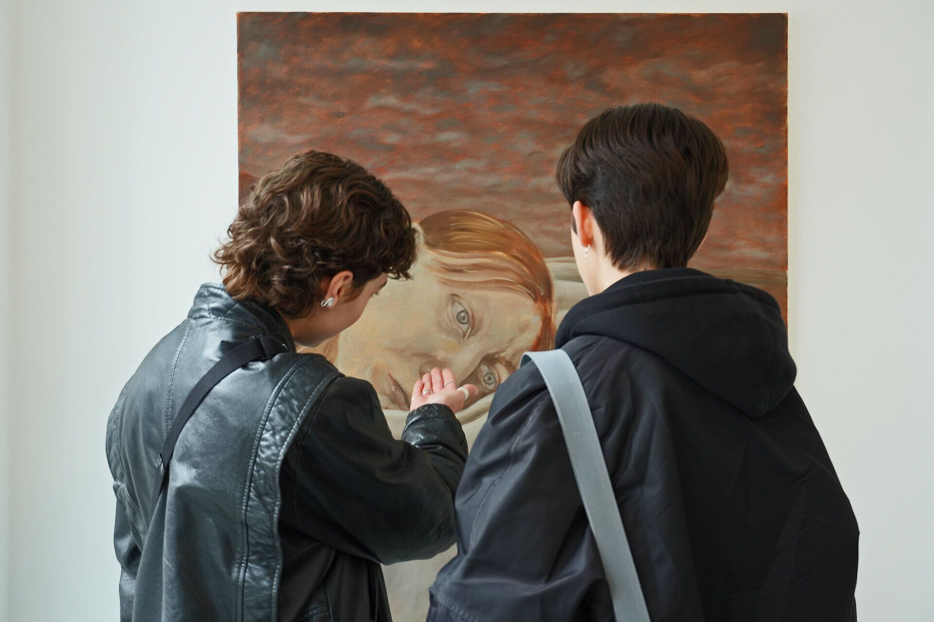 Zwei Besucherinnen betrachten und diskutieren ein Porträtgemälde in einer Kunstausstellung.