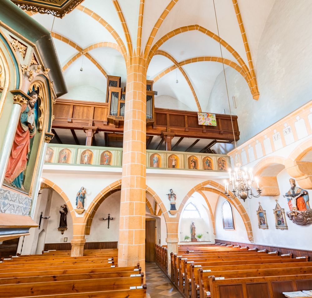Innenraum der Wehrkirche Edlitz mit Kanzel, Bänken, Säule in der Mitte und höher gelegener Chor mit Orgel