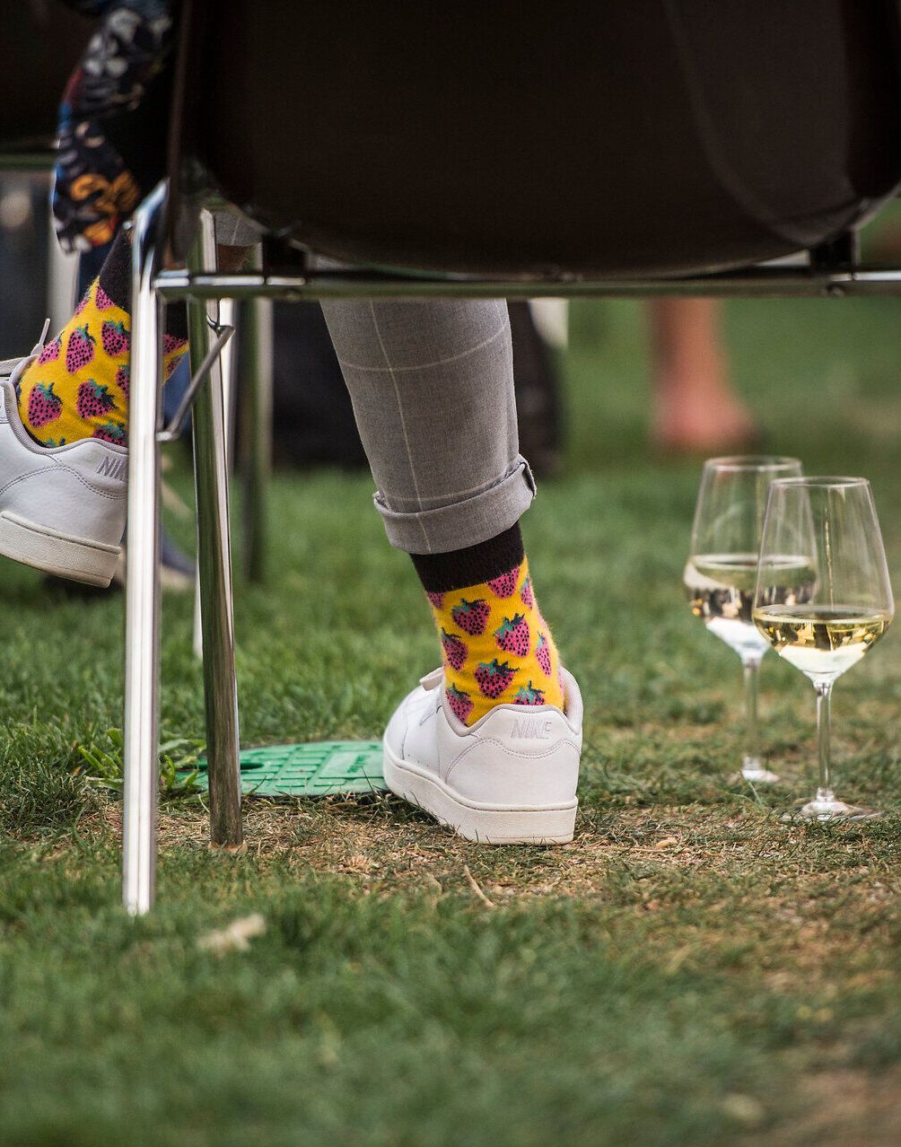 Inmitten der grünen Wiesen und dem sanften Rauschen der Gläser entfaltet sich eine entspannte Atmosphäre. Bunte Socken und weiße Sneakers verleihen dem Moment eine fröhliche Note, während die Gäste den Sommer in vollen Zügen genießen. Ein perfekter Ort, um die Seele baumeln zu lassen und die Schönheit der Natur zu erleben.
