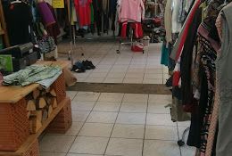 Innenansicht eines Second-Hand-Ladens mit Kleidung auf Kleiderständern.