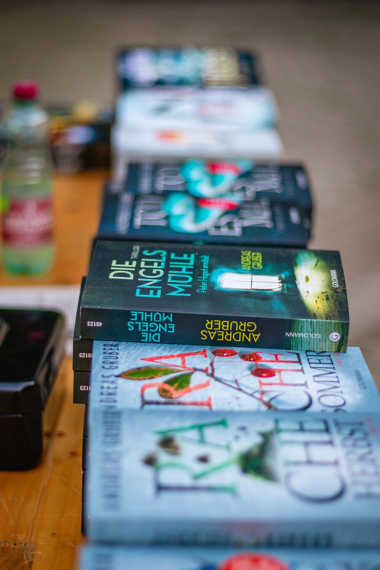 Bunte Buchcover reihen sich aneinander und laden zum Stöbern ein. Die Atmosphäre ist lebhaft und einladend, während die warmen Sonnenstrahlen die Seiten der Bücher zum Glänzen bringen. Hier findet jeder Leser sein persönliches Abenteuer.