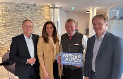 Vier Personen stehen nebeneinander und halten ein Logoschild in den Händen.