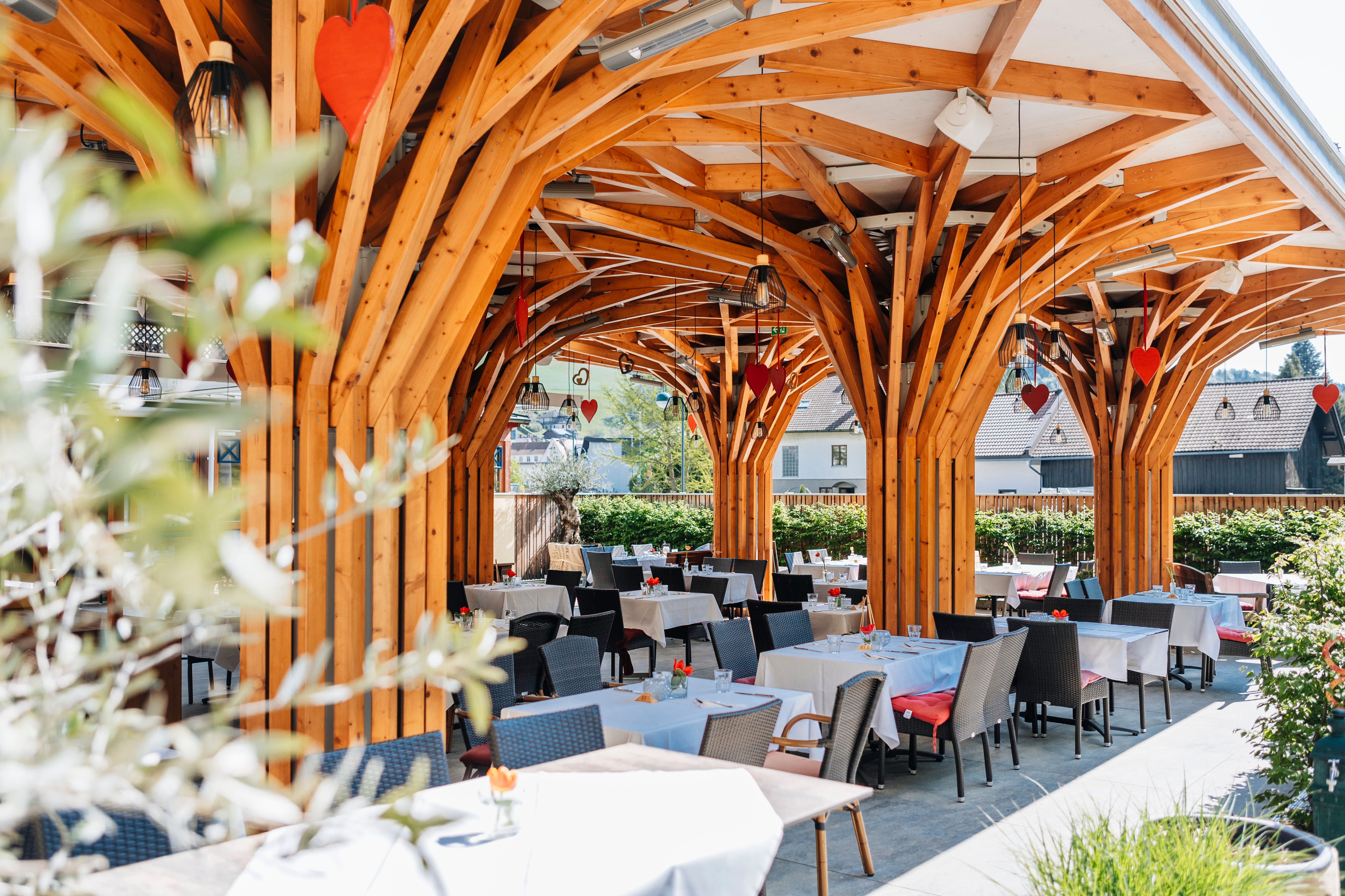 Moderner Gastgarten mit Holzkonstruktion und gedeckten Tischen.