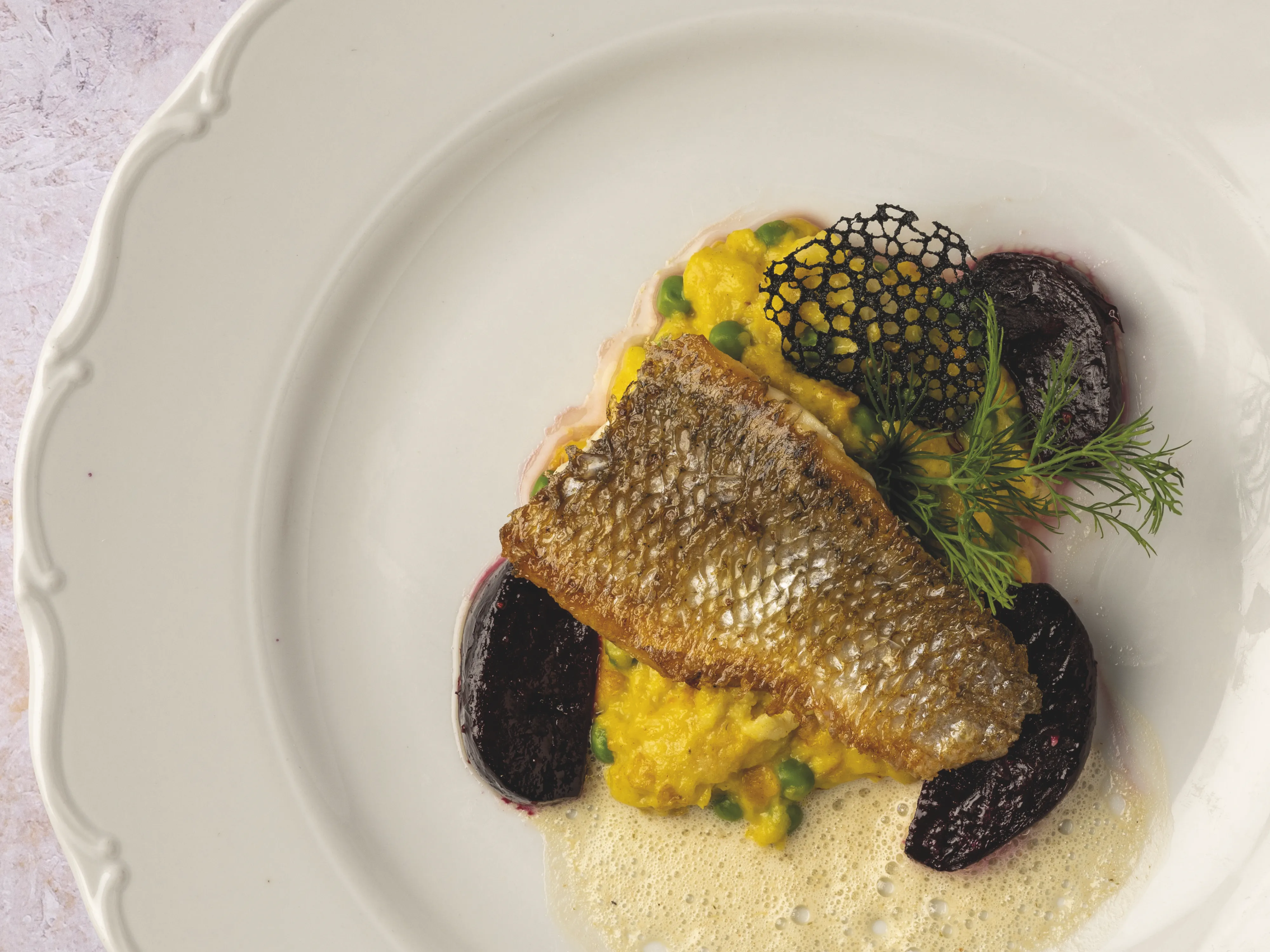 Ein ansprechend angerichtetes Gericht mit Fisch, Gemüse und einer Soße, garniert mit Kräutern.