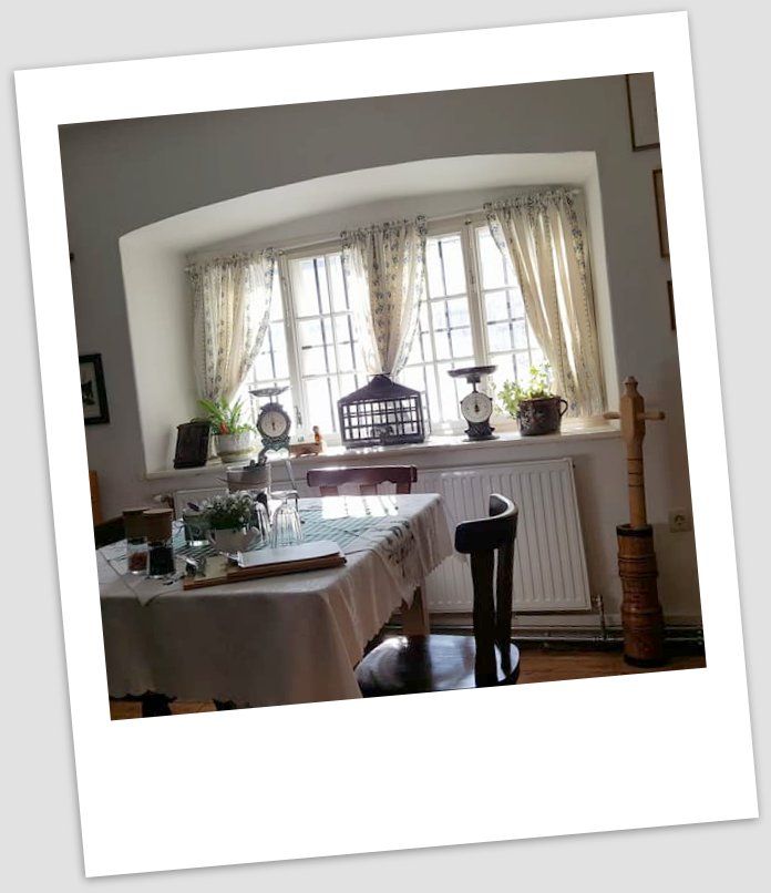 Gemütlicher Essbereich mit Tisch, Stühlen und Fenster mit Vorhängen.