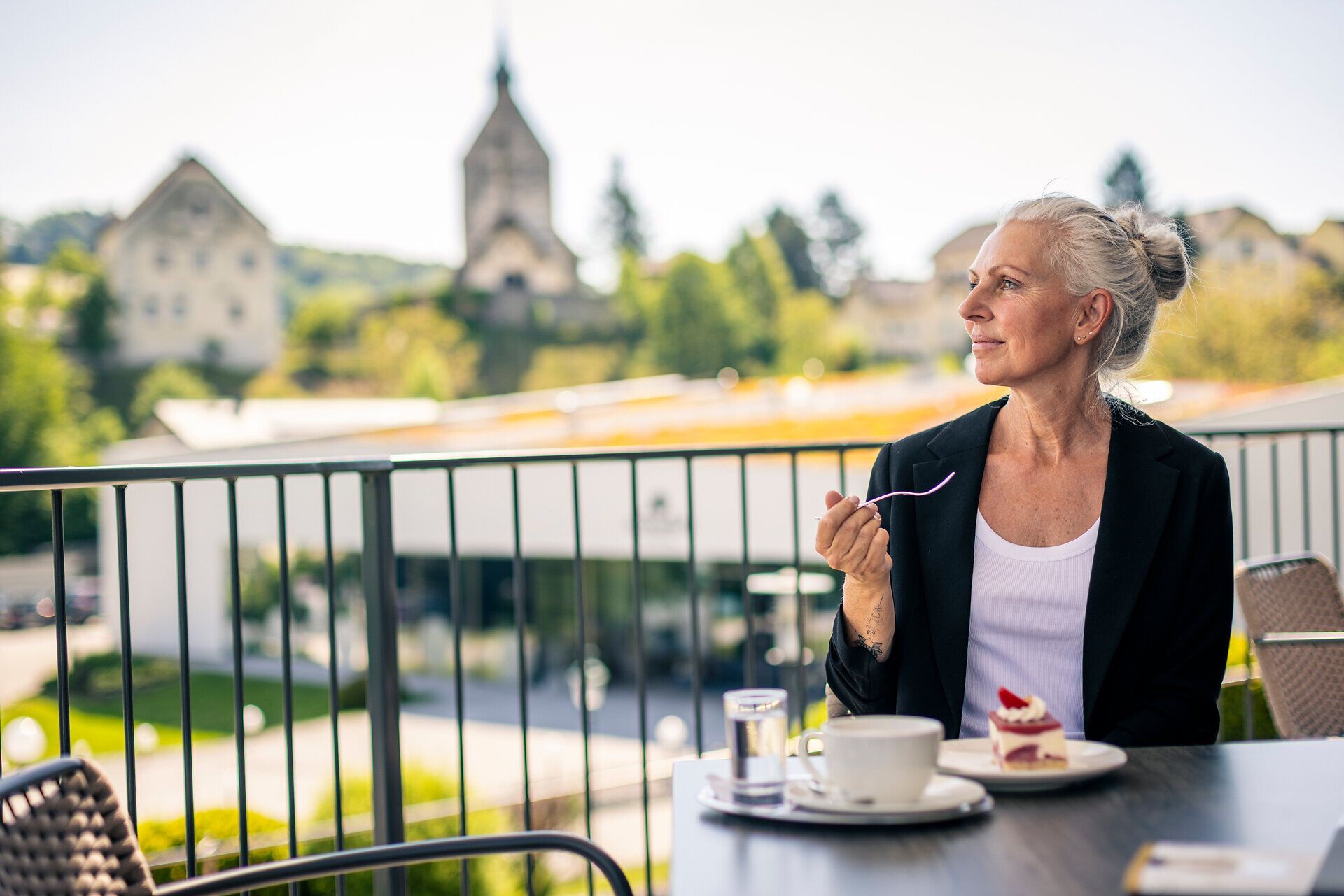 Einer Frau genießt Kaffee und Kuchen auf einer Terrasse.