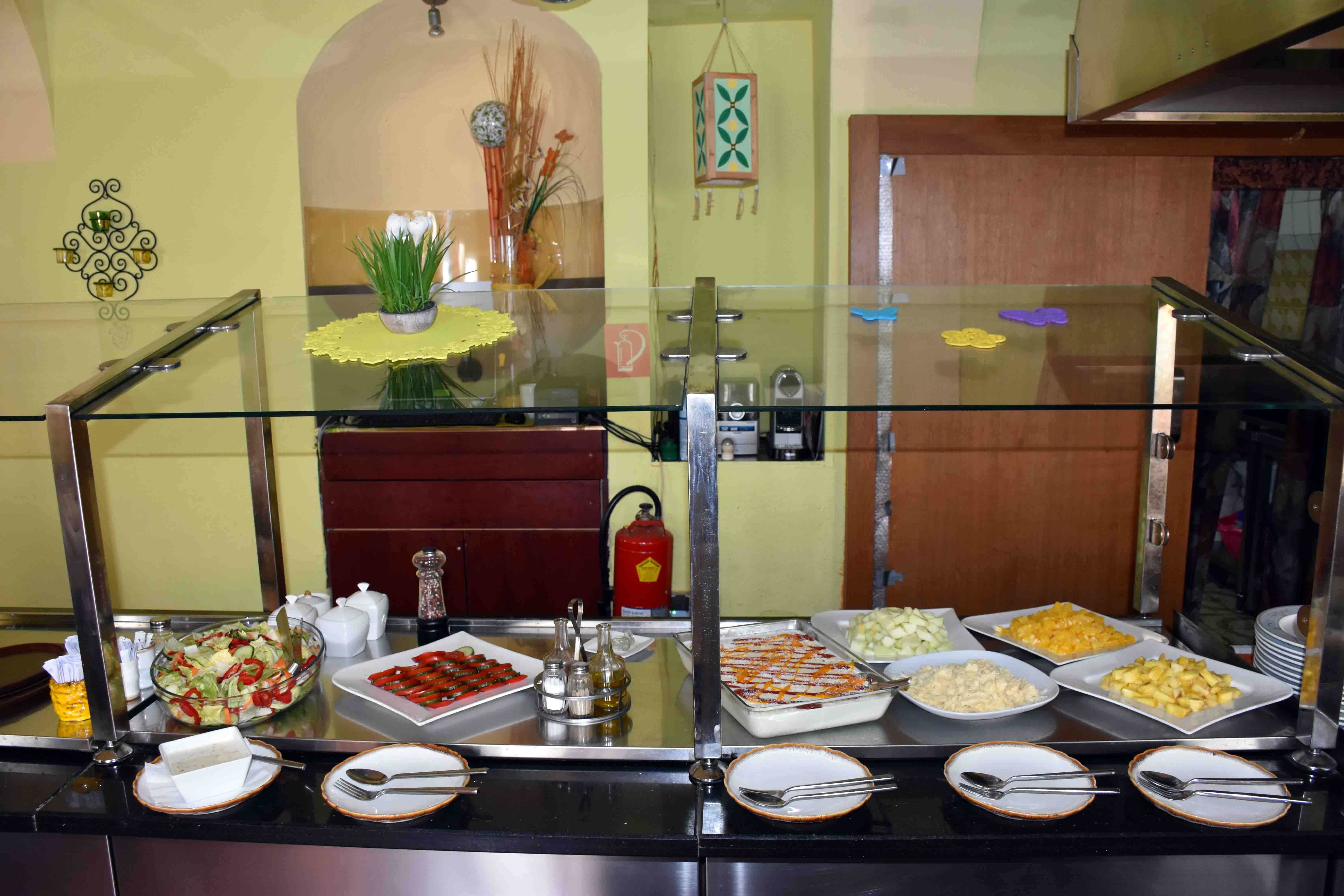 Buffet mit diversen Speisen vor einer grünen Wand.