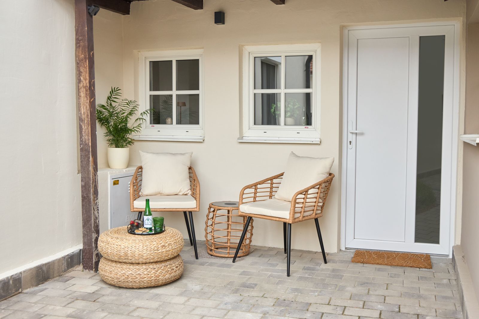 Planted area in front of the entrance door with cozy armchairs and small table
