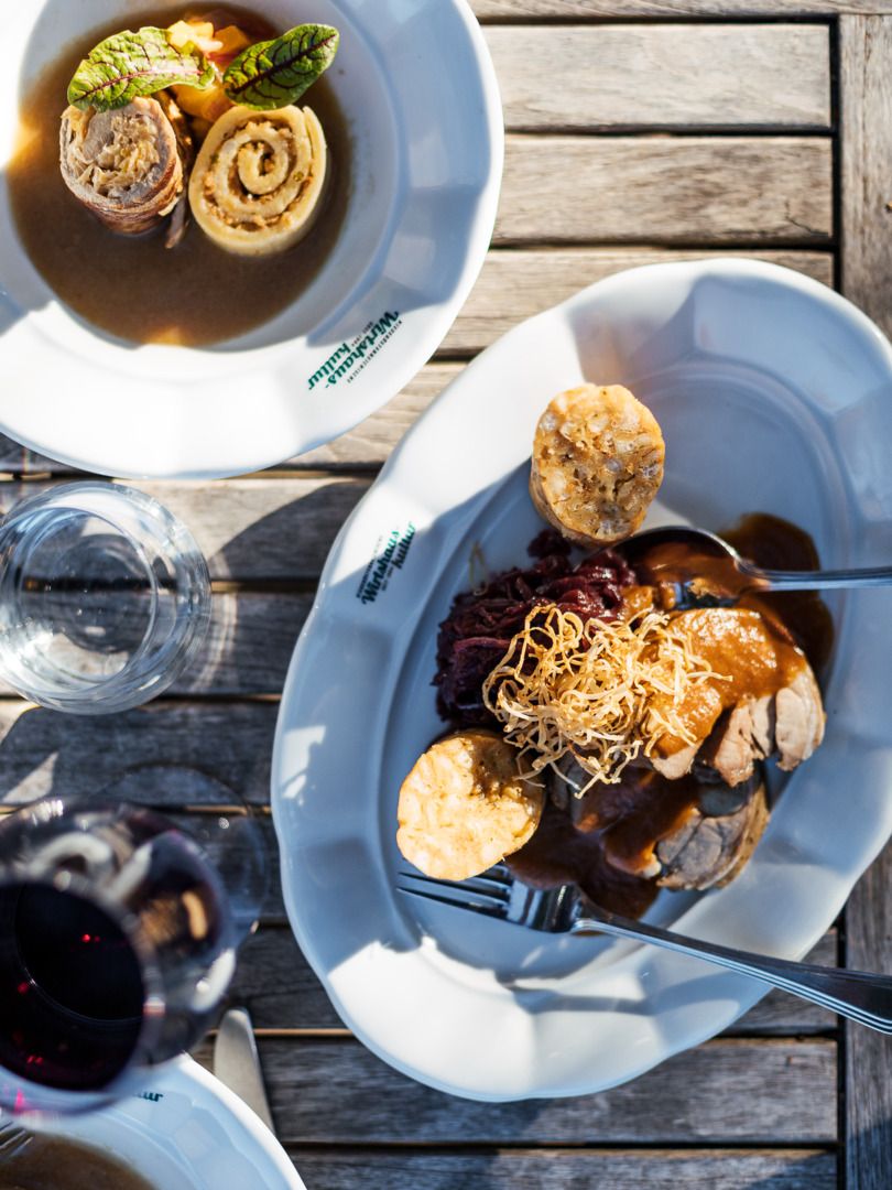 Ein Teller mit Suppe und ein Teller mit einem traditonellen Gericht auf einem Holztisch.