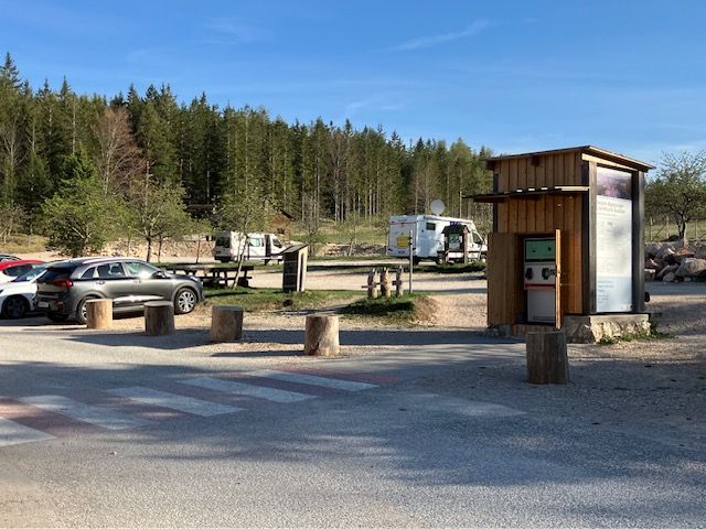 Parkplatz am Naturparkzentrum Hohe Wand mit Autos und Wohnmobilen, umgeben von Wald.