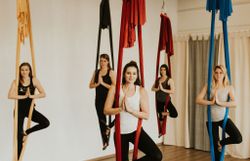 Frauen, die in einem von der Decke hängenden Tuch Turnübungen machen