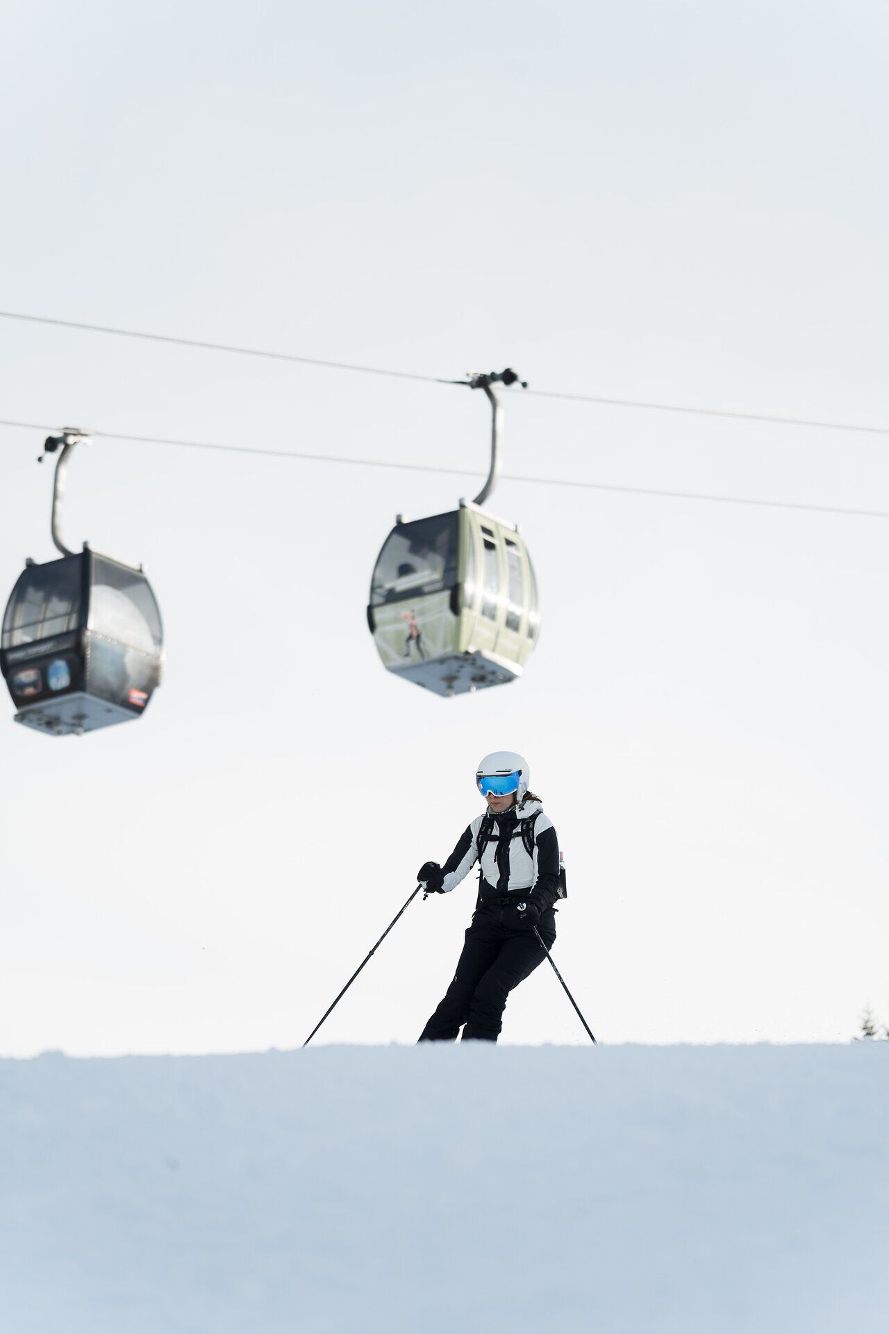 Skifahrerin auf einer verschneiten Piste am Semmering Hirschenkogel, im Hintergrund die Kabinenbahn.
