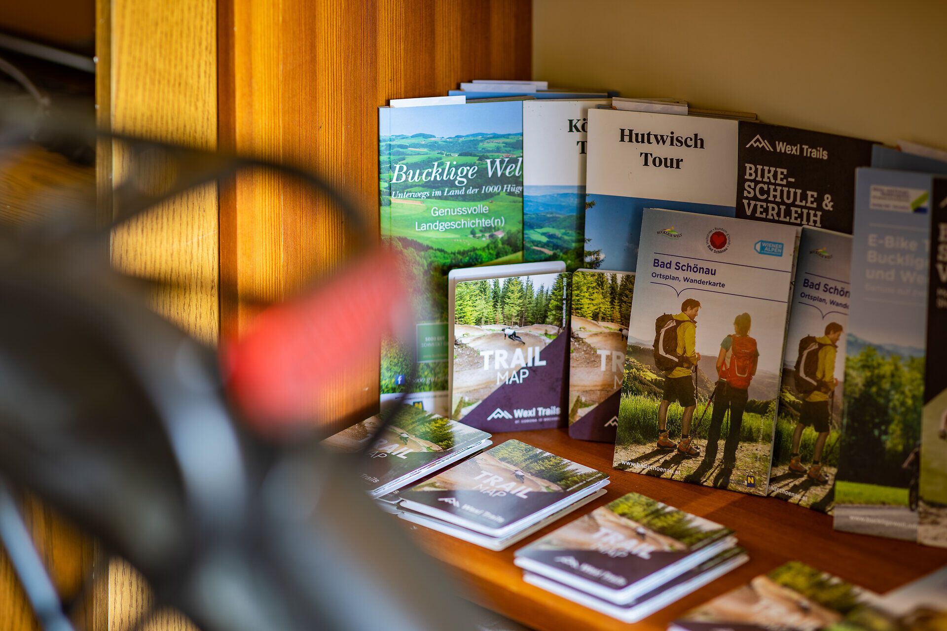 In einem Regal wird im Vitalzeit Hotel Weber eine Auswahl von Prospekten zu den Themen Bucklige Welt, Mountainbiken, E-Biken und Wandern angeboten.