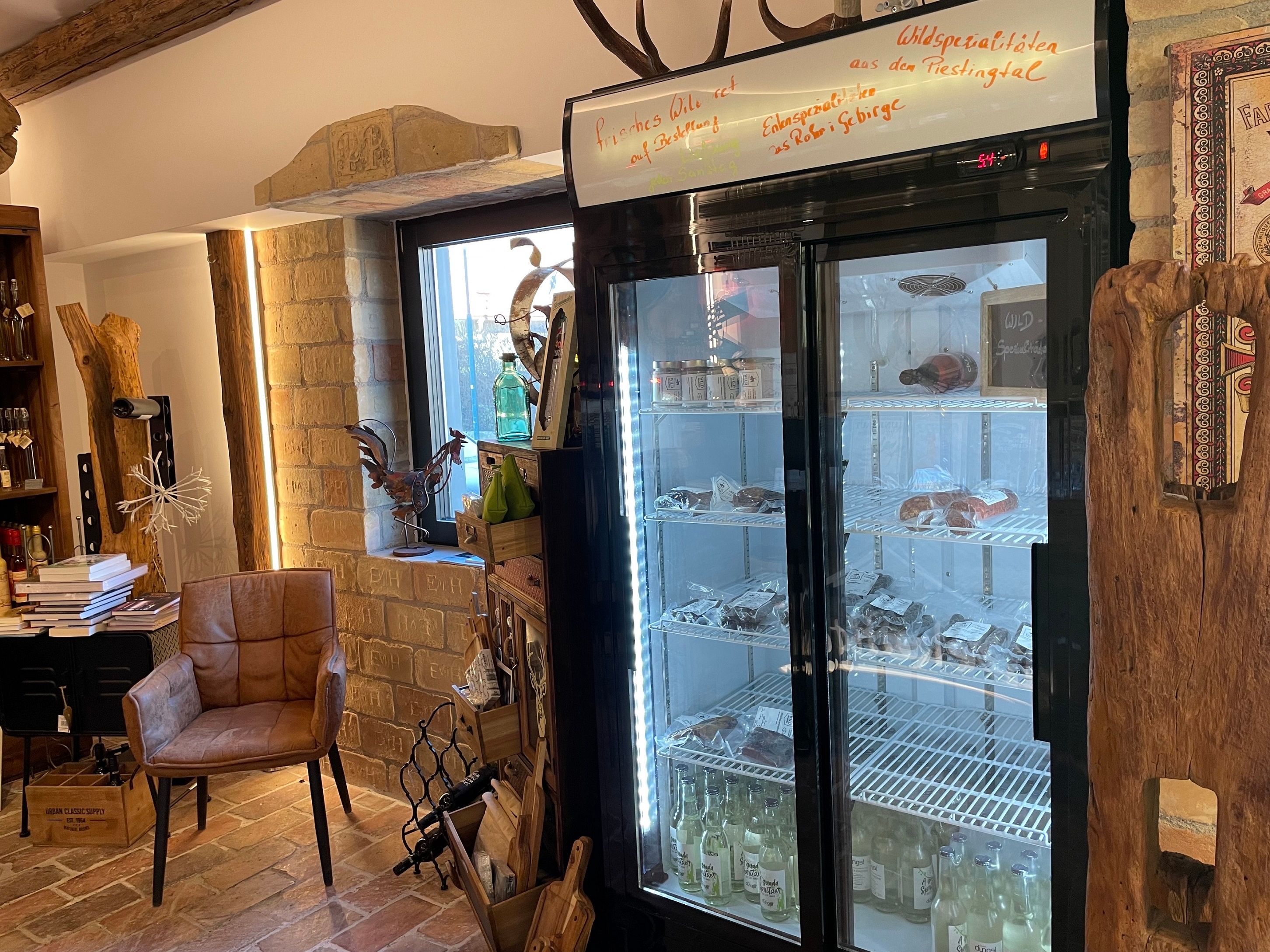 Innenansicht eines Ladens mit Kühlschrank, Stuhl und Dekorationen.