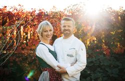 Ein Mann in Kochjacke und eine Frau in traditioneller Kleidung halten sich in den Armen.