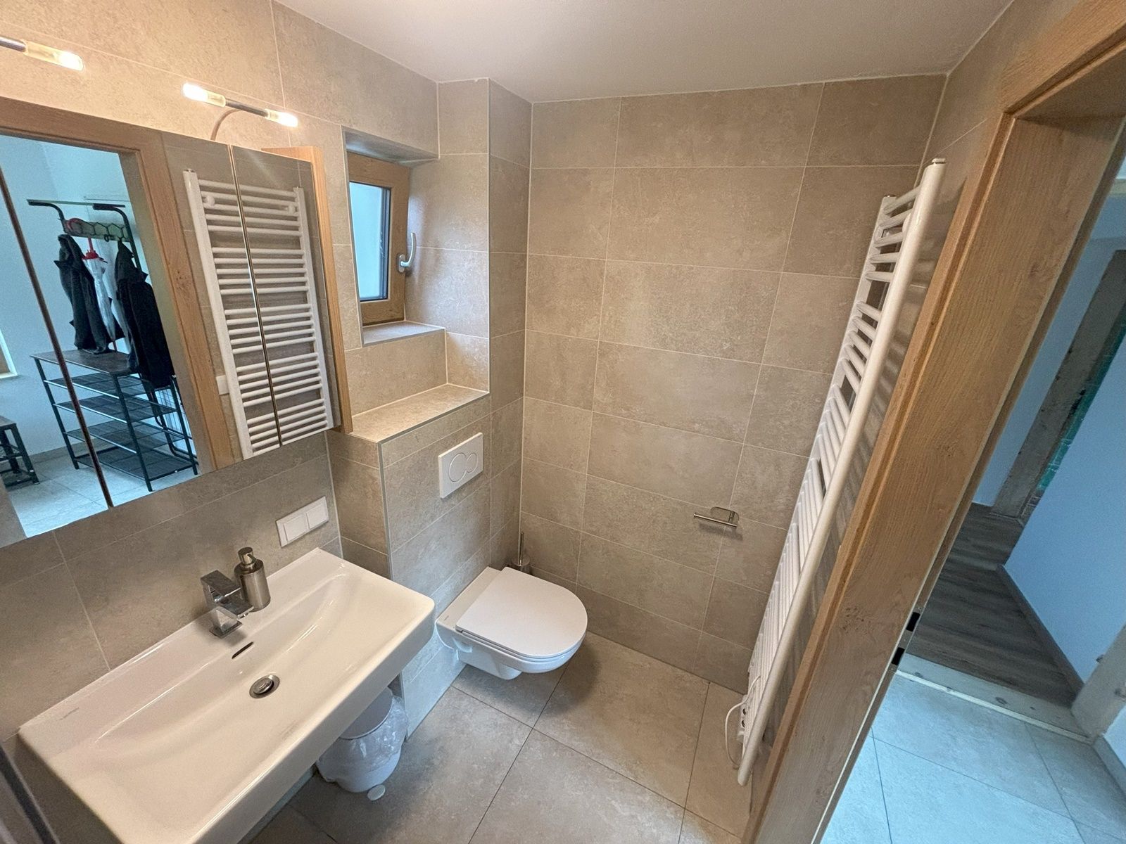 Modernes Badezimmer mit Waschbecken, WC und Handtuchheizkörper.