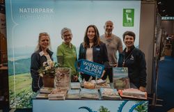 Fünf Personen mit dem Schild Wiener Alpen in Niederösterreich vor dem Stand Naturpark Hohe Wand 