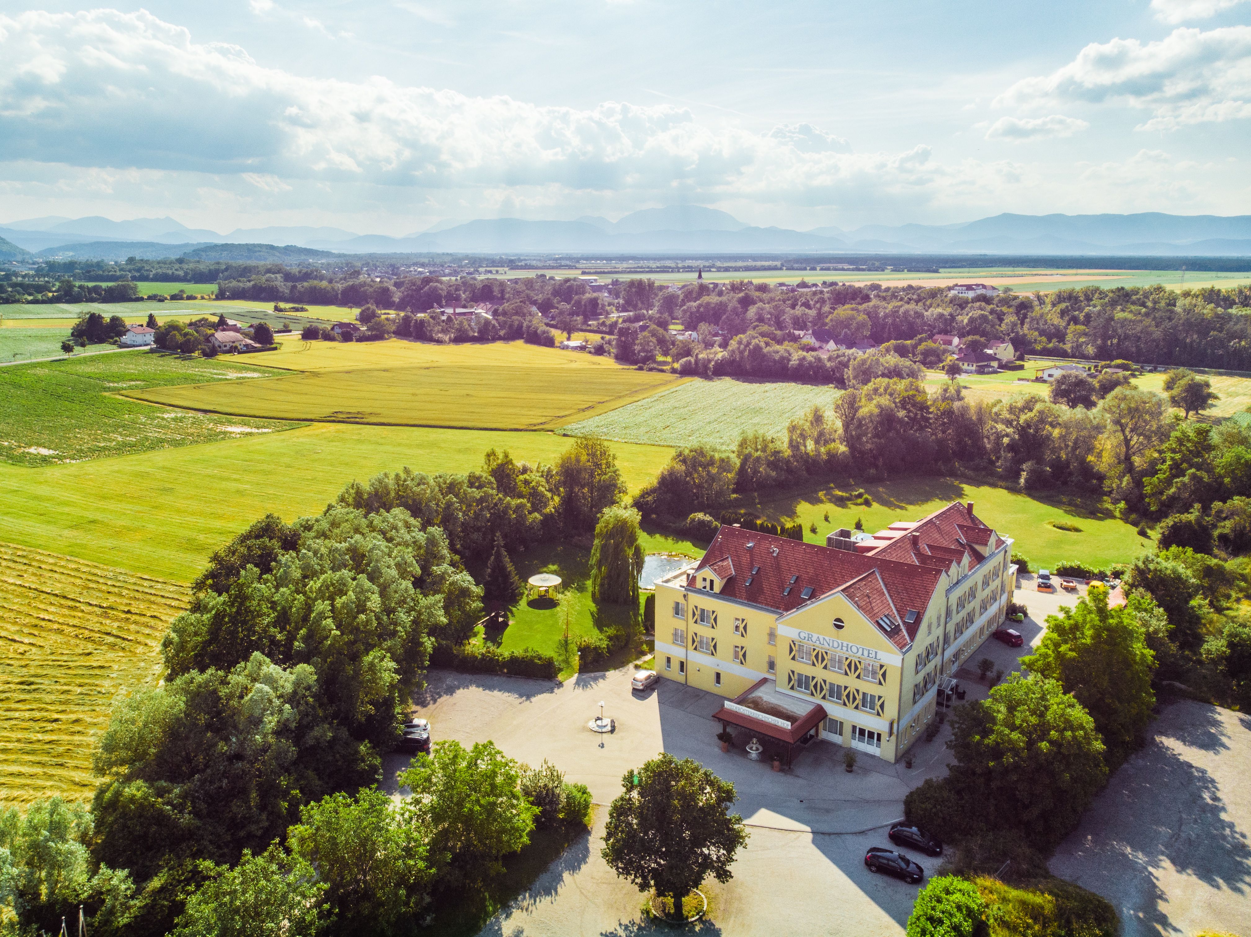 Luftaufnahme eines Hotels inmitten einer ländlichen Landschaft mit Feldern und Bäumen.