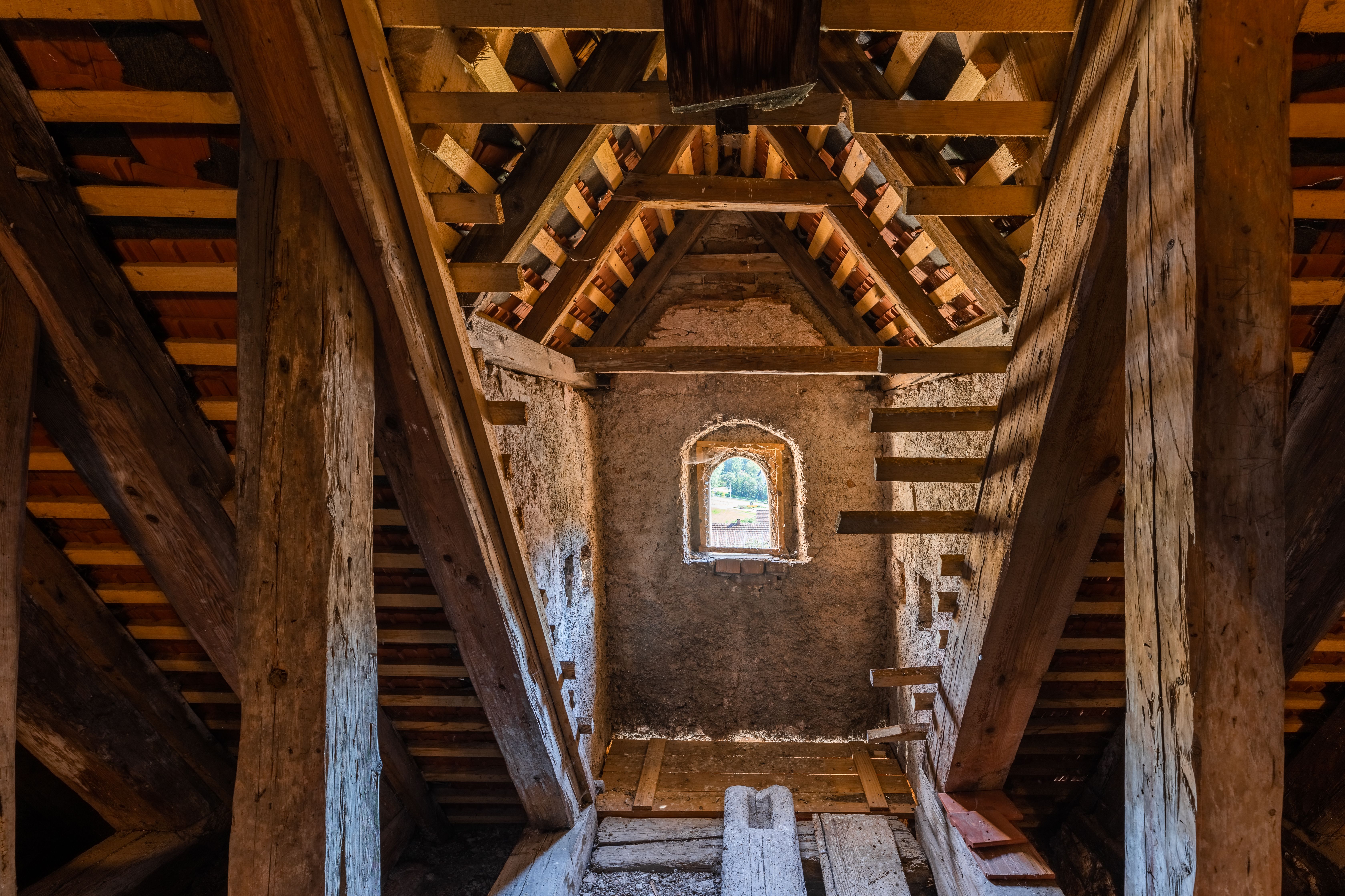 Hölzernes Dachgeschoss der Wehrkirche Edlitz mit kleiner Öffnung in der Steinwand und vielen Balken