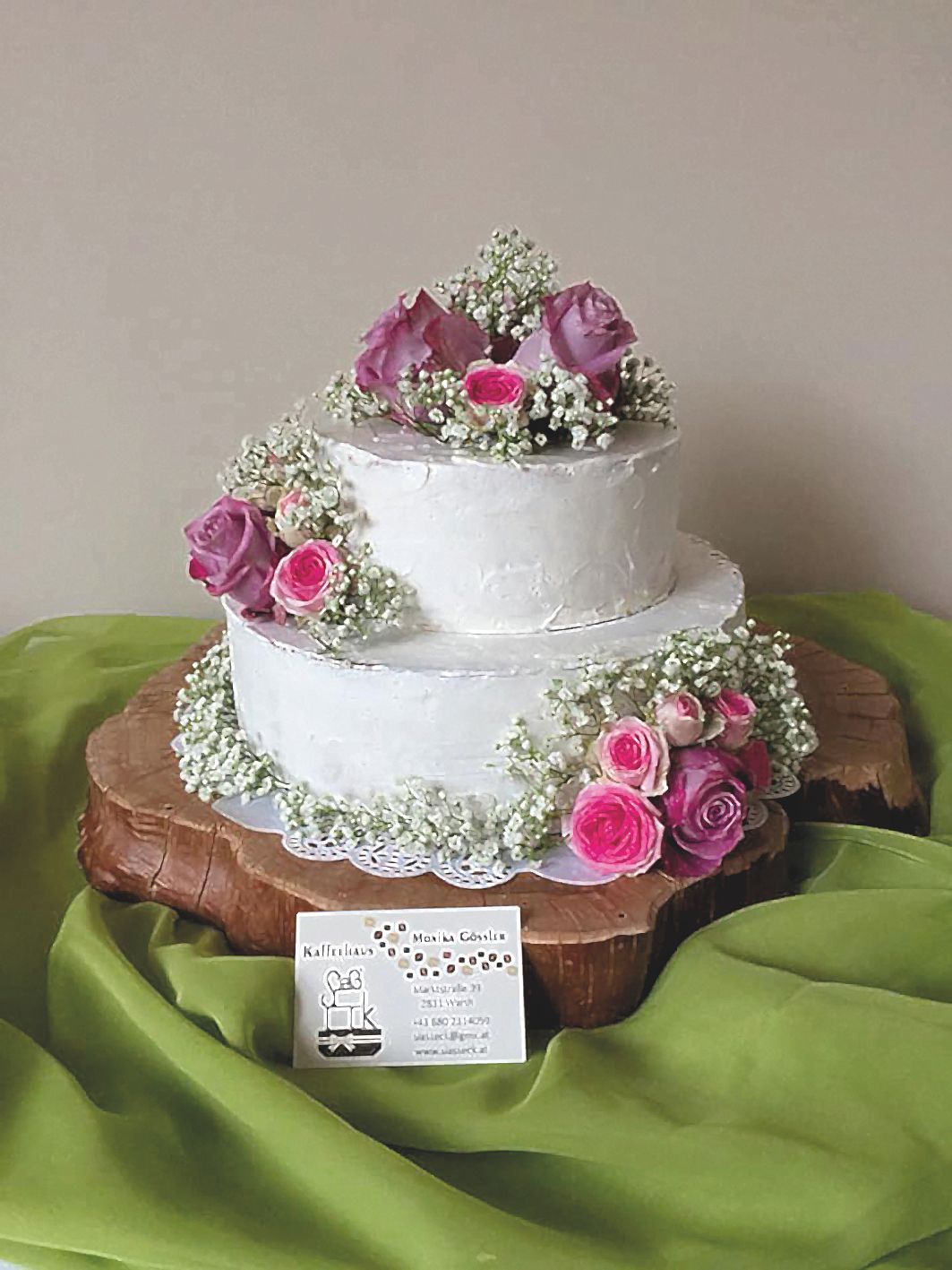 Eine zweistöckige Torte mit weißer Creme und Blumen verziert.