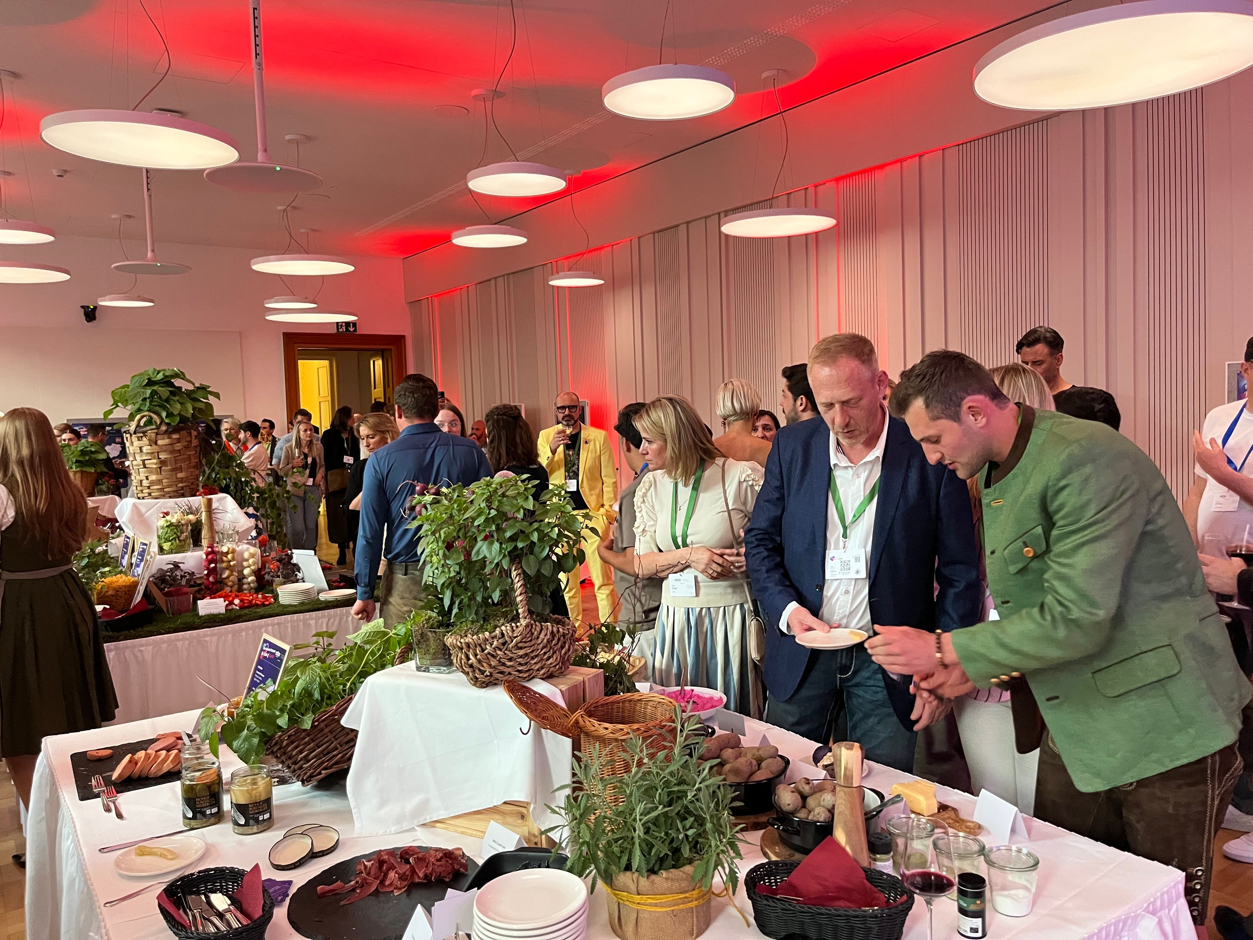 Ein Tisch mit regionalen Produkten bei einer Veranstaltung, daneben Menschen.