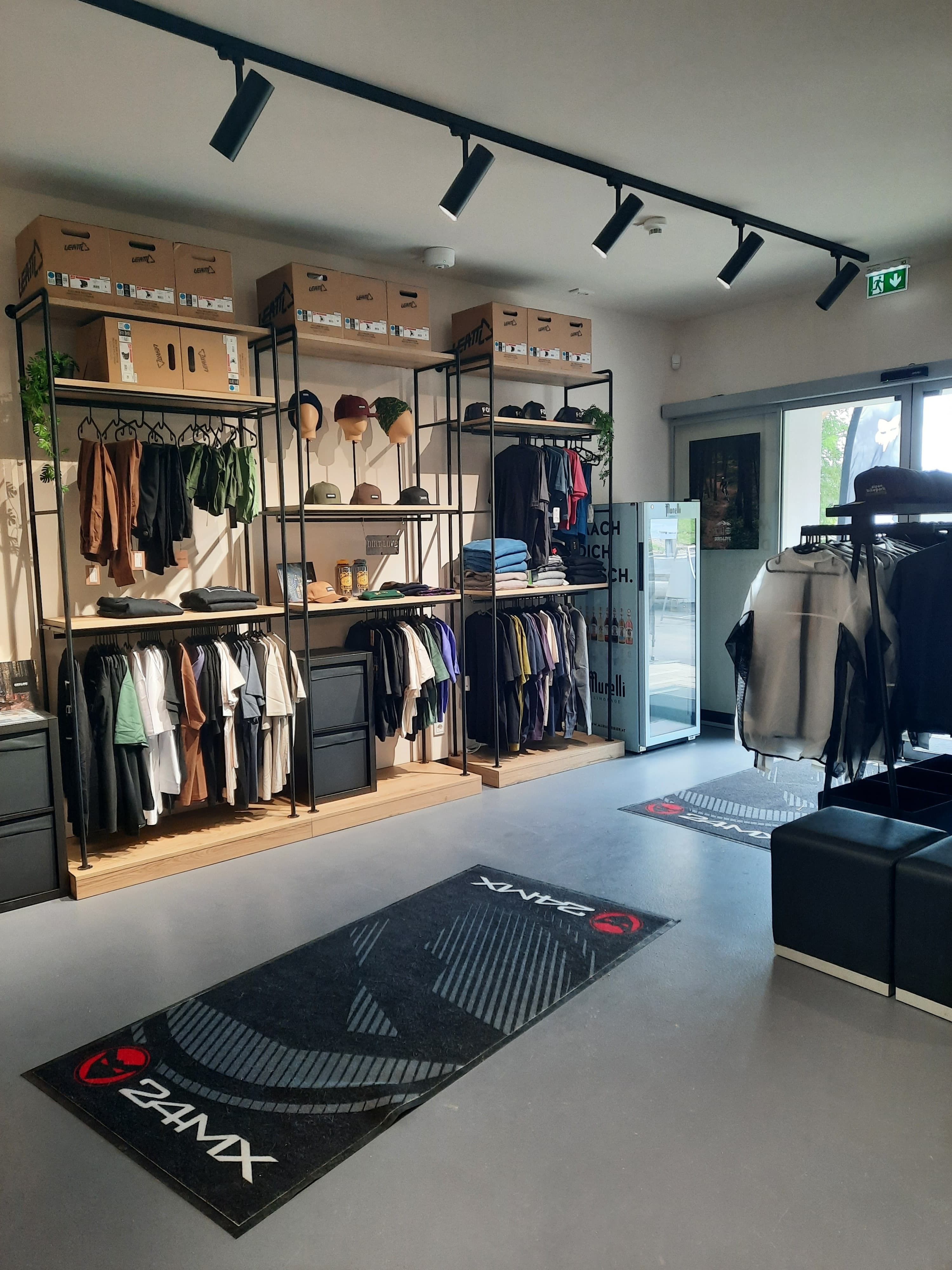 Innenansicht eines Fahrradgeschäfts mit Kleidung und Accessoires auf Regalen.