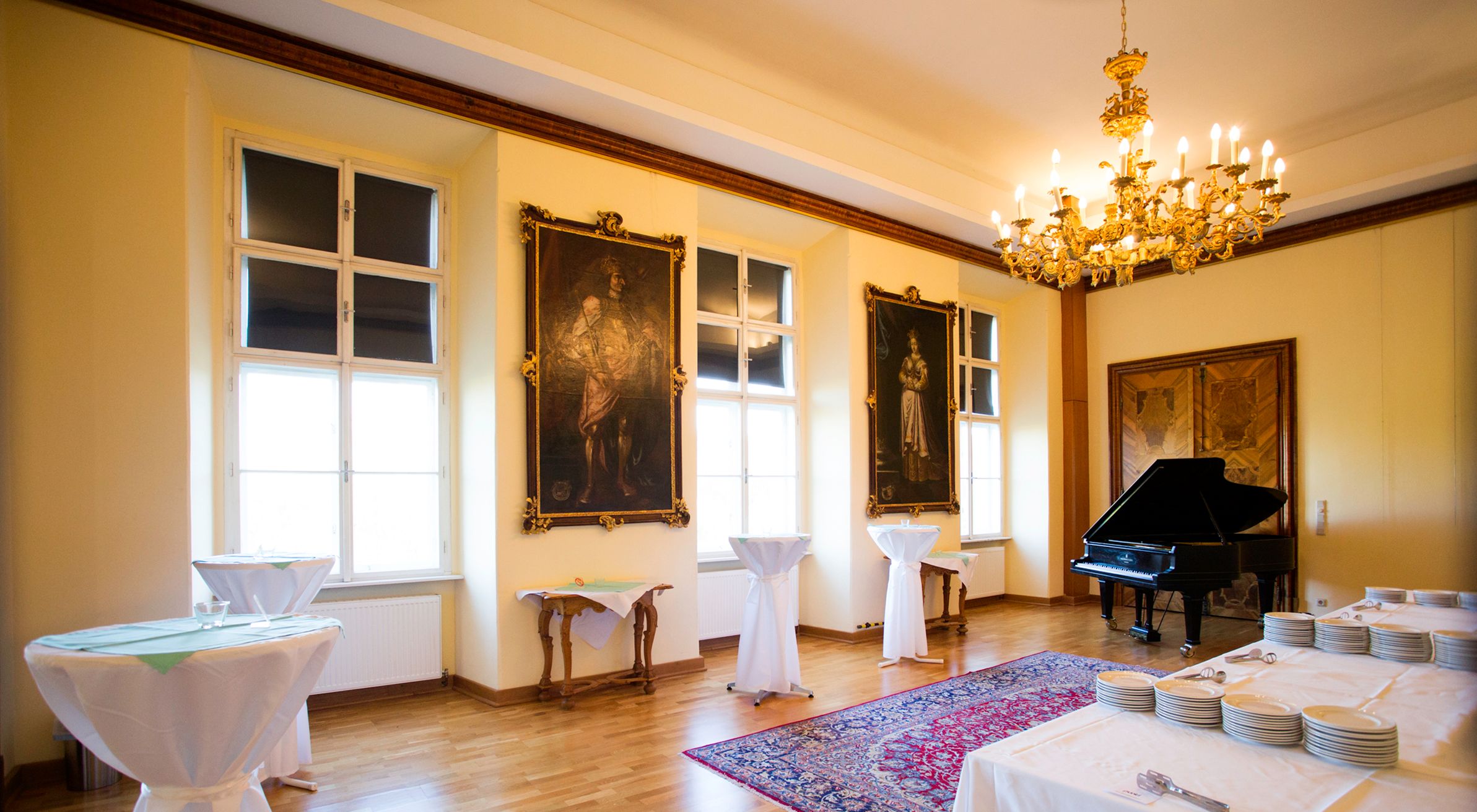 Prunkvoller Raum mit flügel und hohen Fenster, vor dem Stehtische platziert wurden