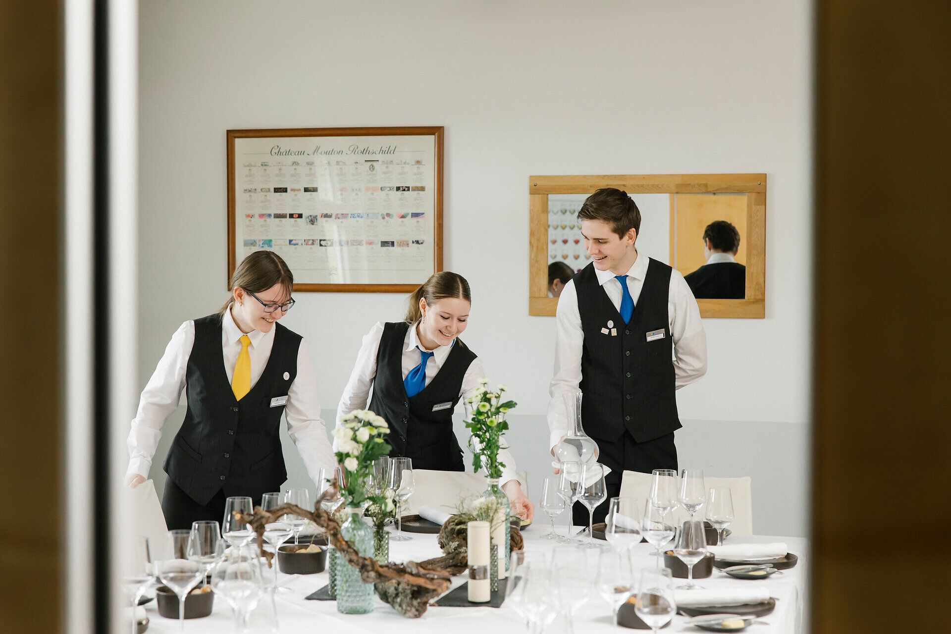 Servicekräfte decken gemeinsam einen festlich gedeckten Tisch in einem Restaurant.