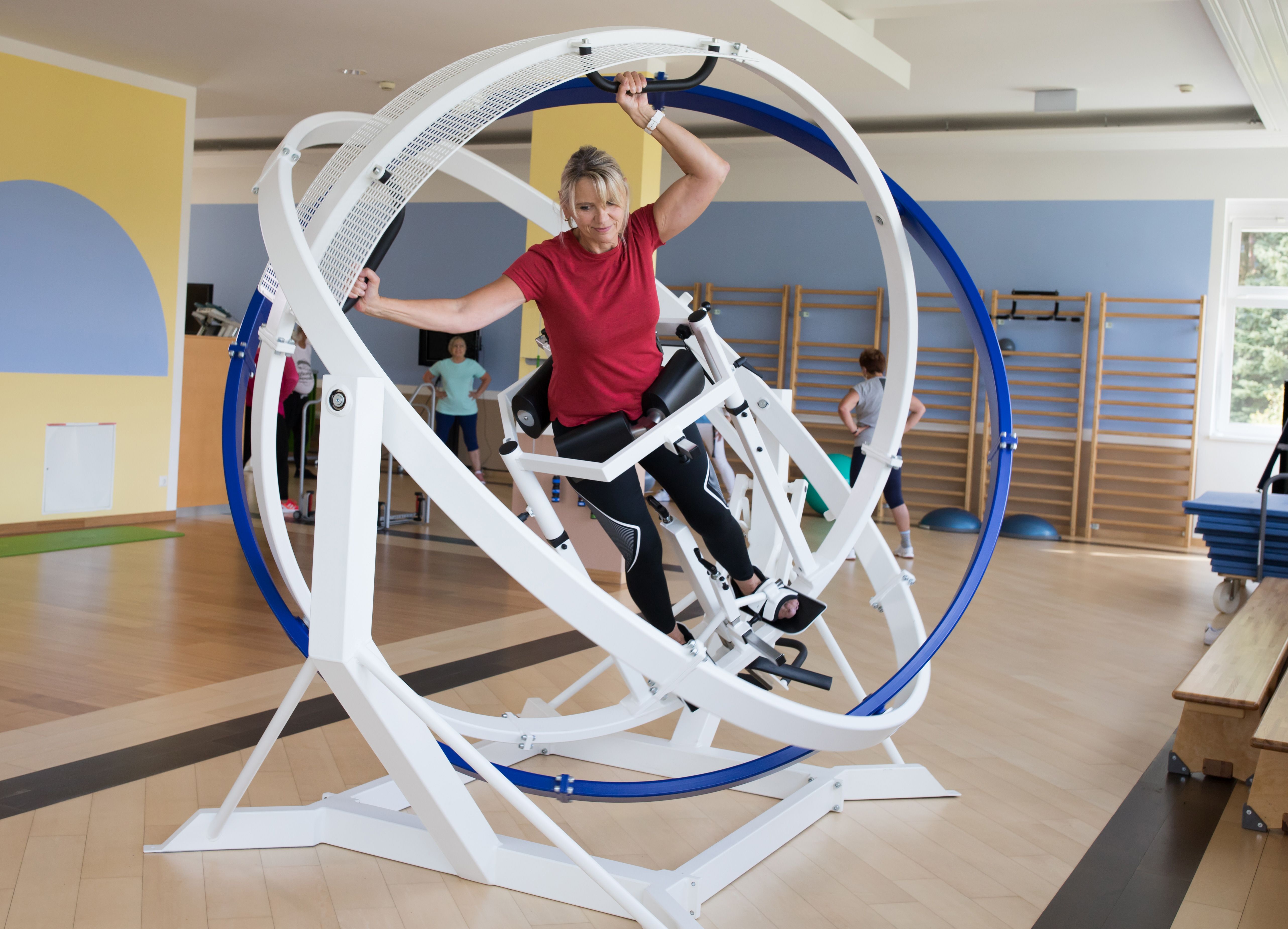 Eine Frau trainiert in einem Fitnessgerät mit rotierenden Ringen in einem Fitnessstudio.