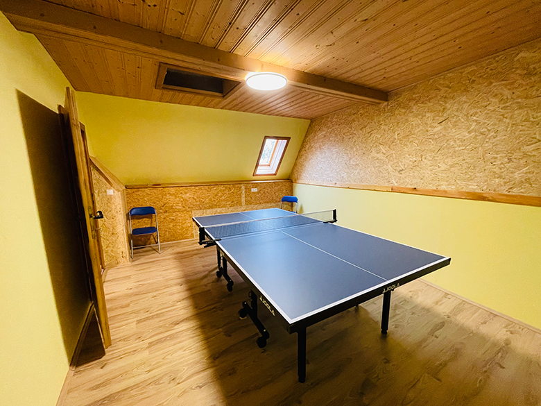 A playroom with table tennis table, yellow walls and wooden ceiling.