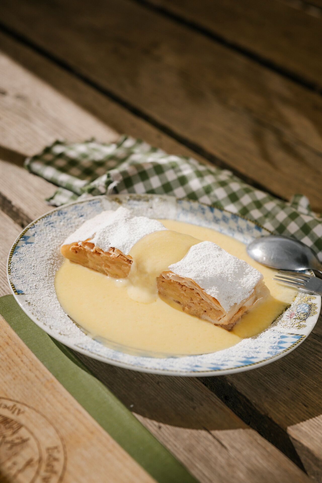 Apfelstrudel mit Vanillesauce und Schlagobers auf einem Teller in der Edelweißhütte am Schneeberg