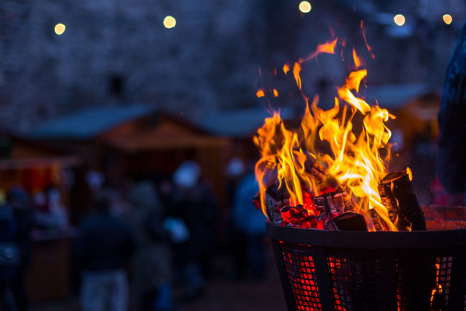 Offenes Feuer in einer Feuerschale auf einem Weihnachtsmarkt bei Nacht.