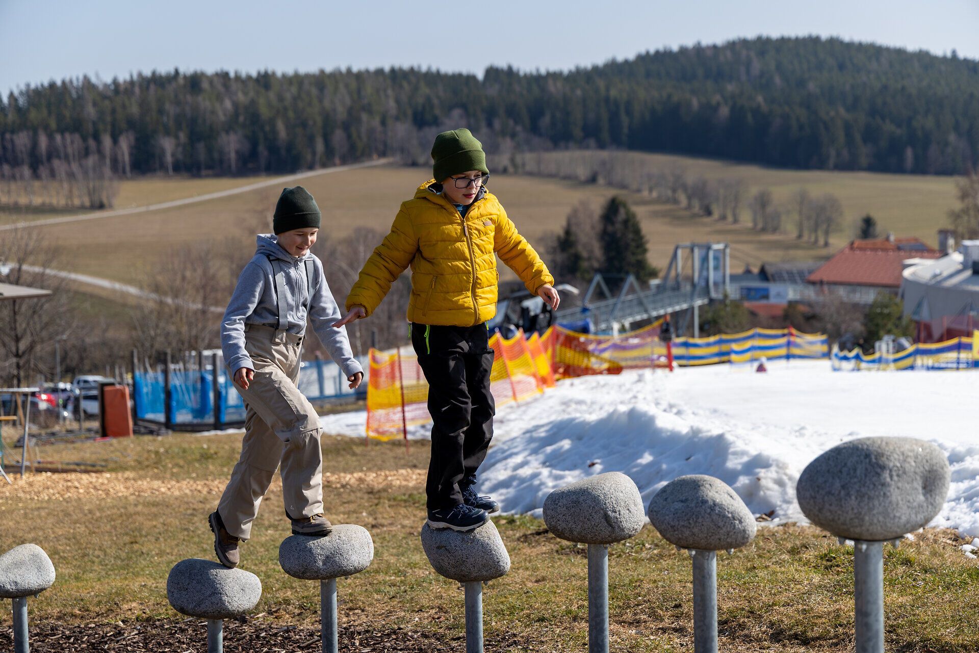Zwei Kinder balancieren über ein Hindernis mit Trittelementen im Motorikpark der Wexl Arena