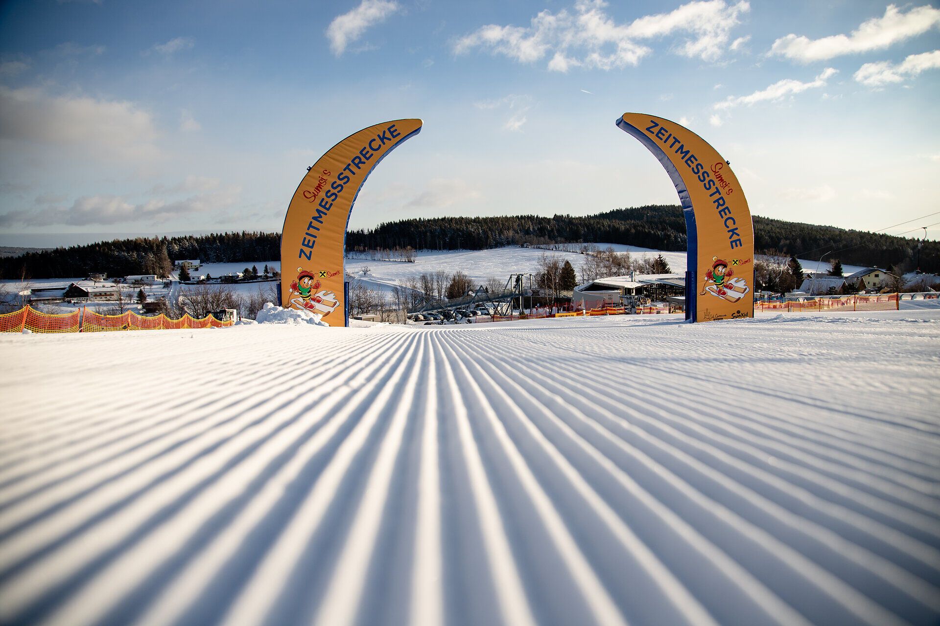 Frisch präparierte Skipiste mit zwei Torbögen im Kinderskiland der Wexl Arena