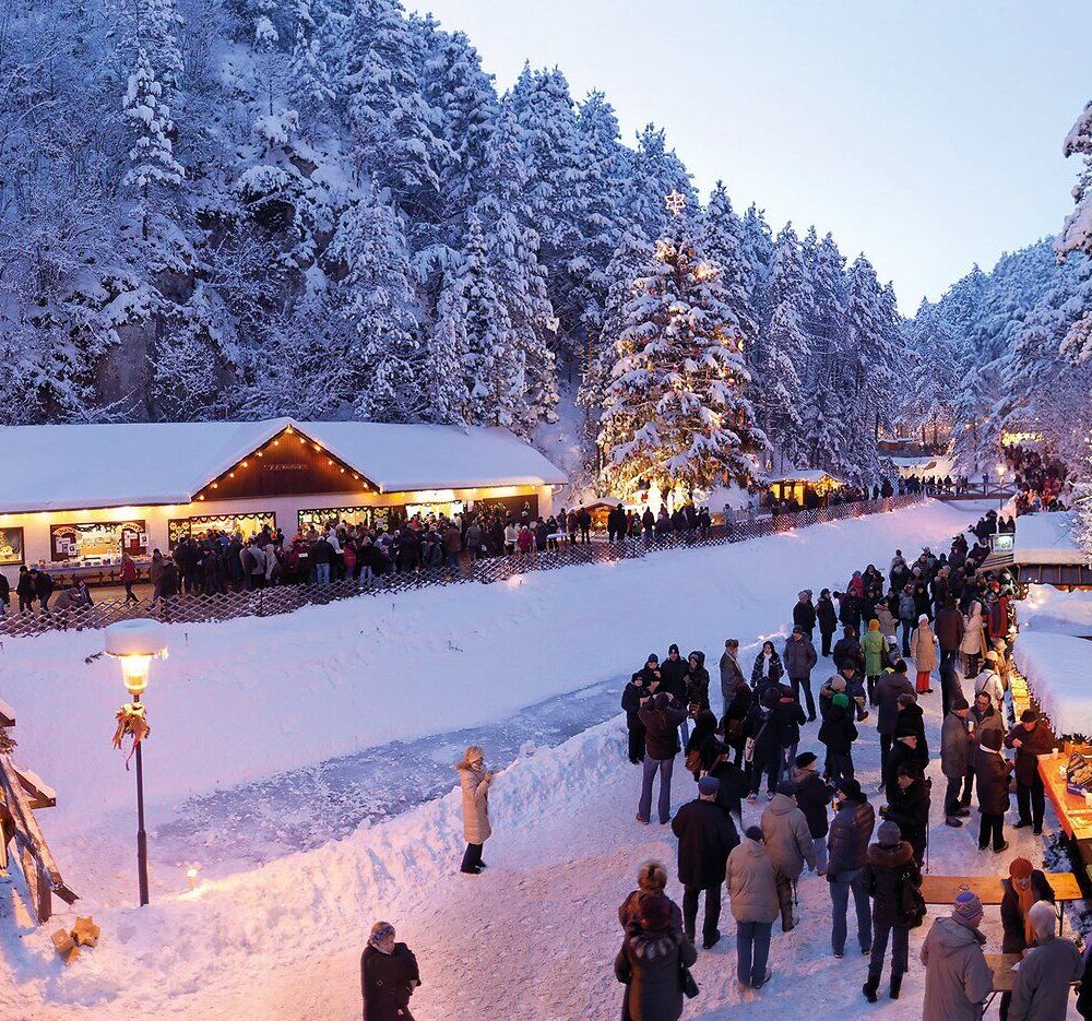 In der malerischen Winterlandschaft der Johannesbachklamm erstrahlen die festlich geschmückten Stände im warmen Licht der Adventszeit. Die schneebedeckten Bäume umrahmen die fröhlichen Besucher, die sich bei Glühwein und regionalen Köstlichkeiten auf die besinnliche Zeit einstimmen.
