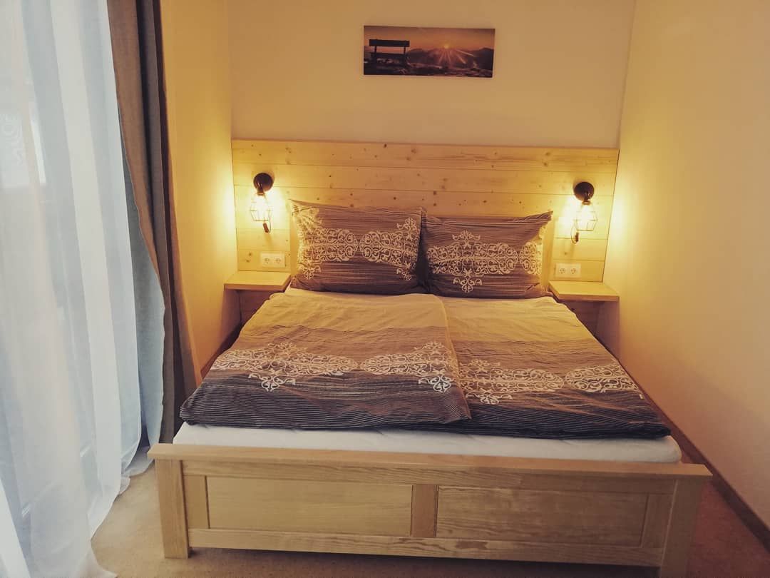 Gemütliches Doppelzimmer mit Holzbett und Nachttischlampen.