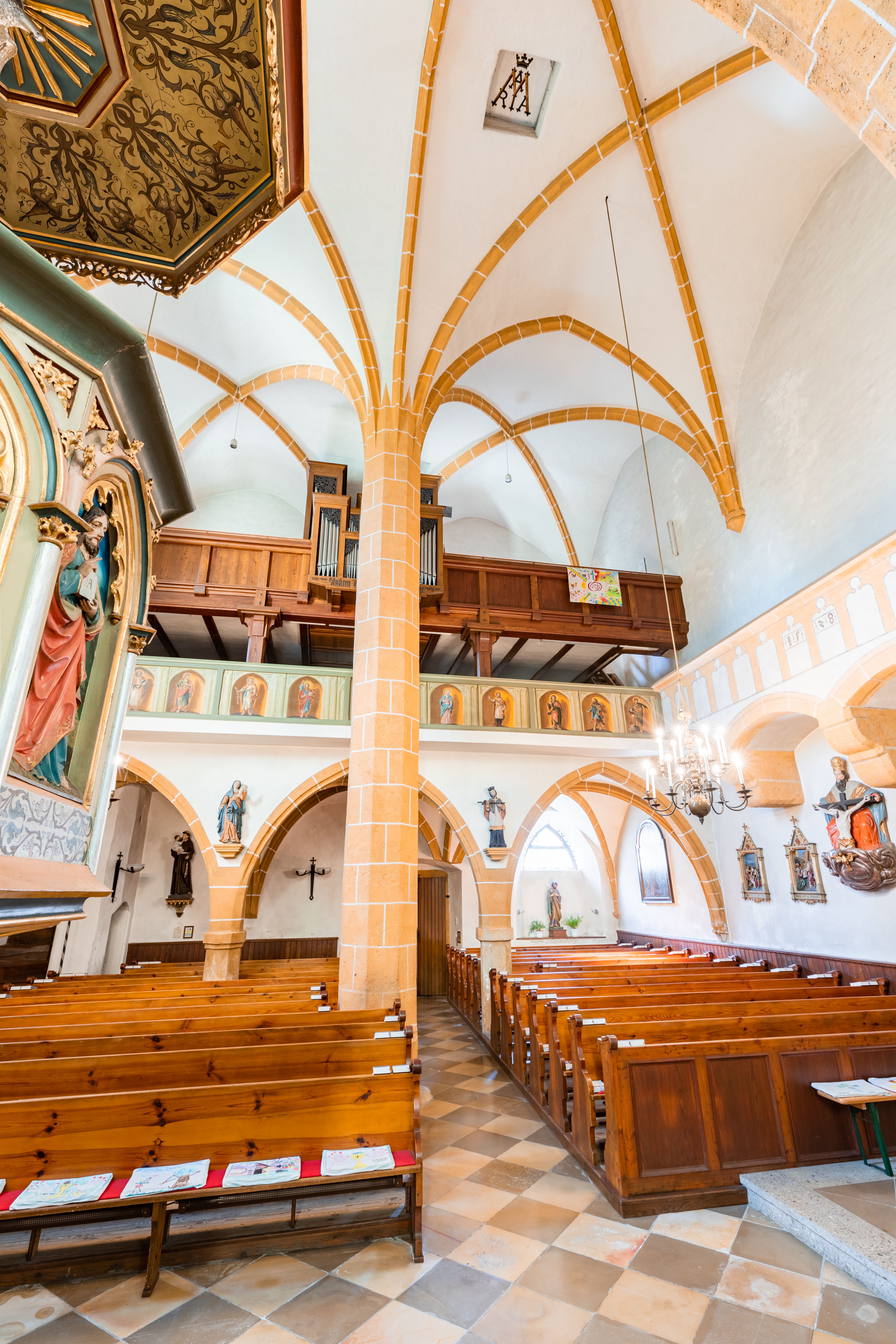 Innenraum der Wehrkirche Edlitz mit Kanzel, Bänken, Säule in der Mitte und höher gelegener Chor mit Orgel