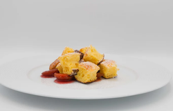 Ein Teller mit Sauerrahmschmarrn und Zwetschkenröster vor weißem Hintergrund. 