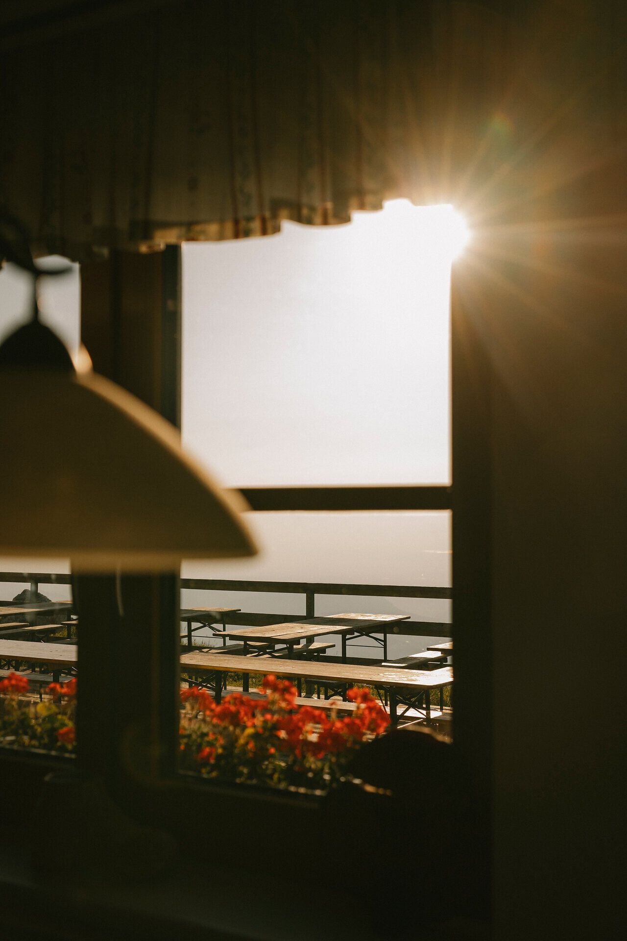 Sunlight streams through the window of the fishing cabin on Schneeberg onto the patio with benches