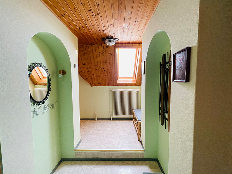 An anteroom with wooden ceiling, skylight, mirror and bench.